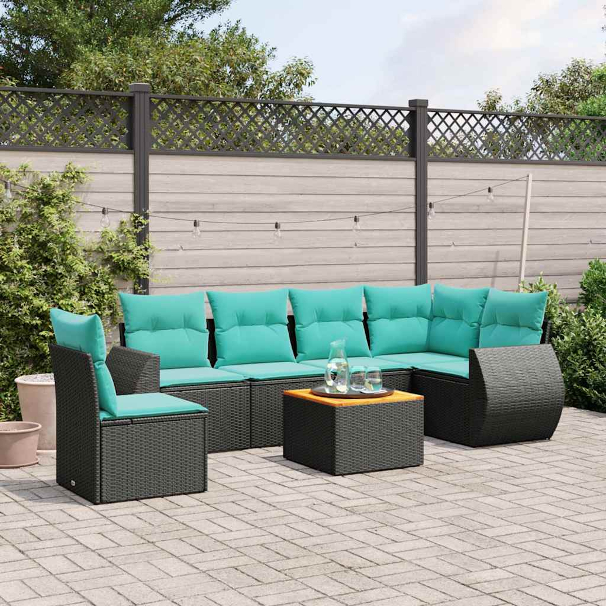 Ein dunkles Outdoor-Sofa mit türkisfarbenen Kissen und einem kleinen Tisch.