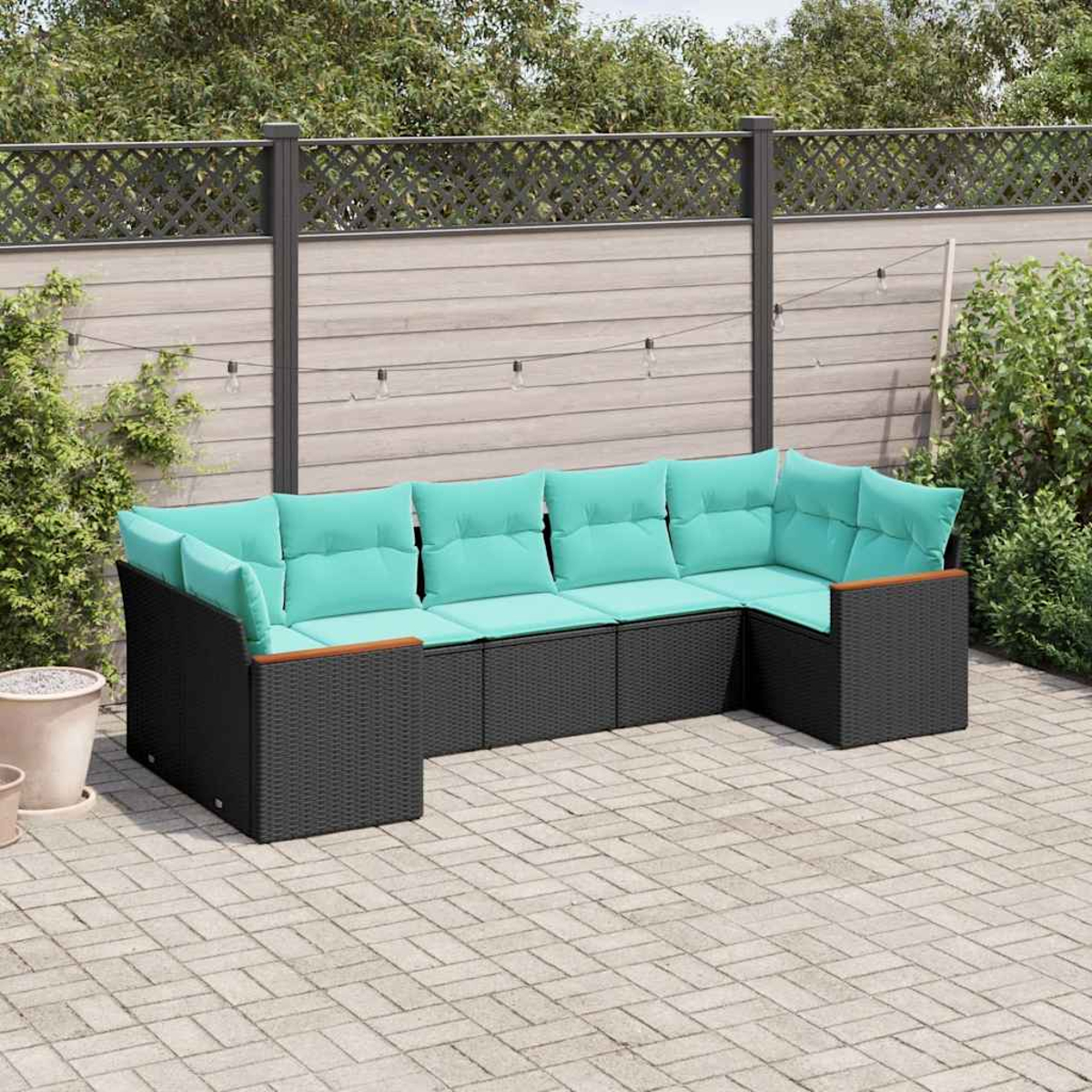 Un sofá modular exterior gris oscuro con cojines azul turquesa brillante está en un patio pavimentado.