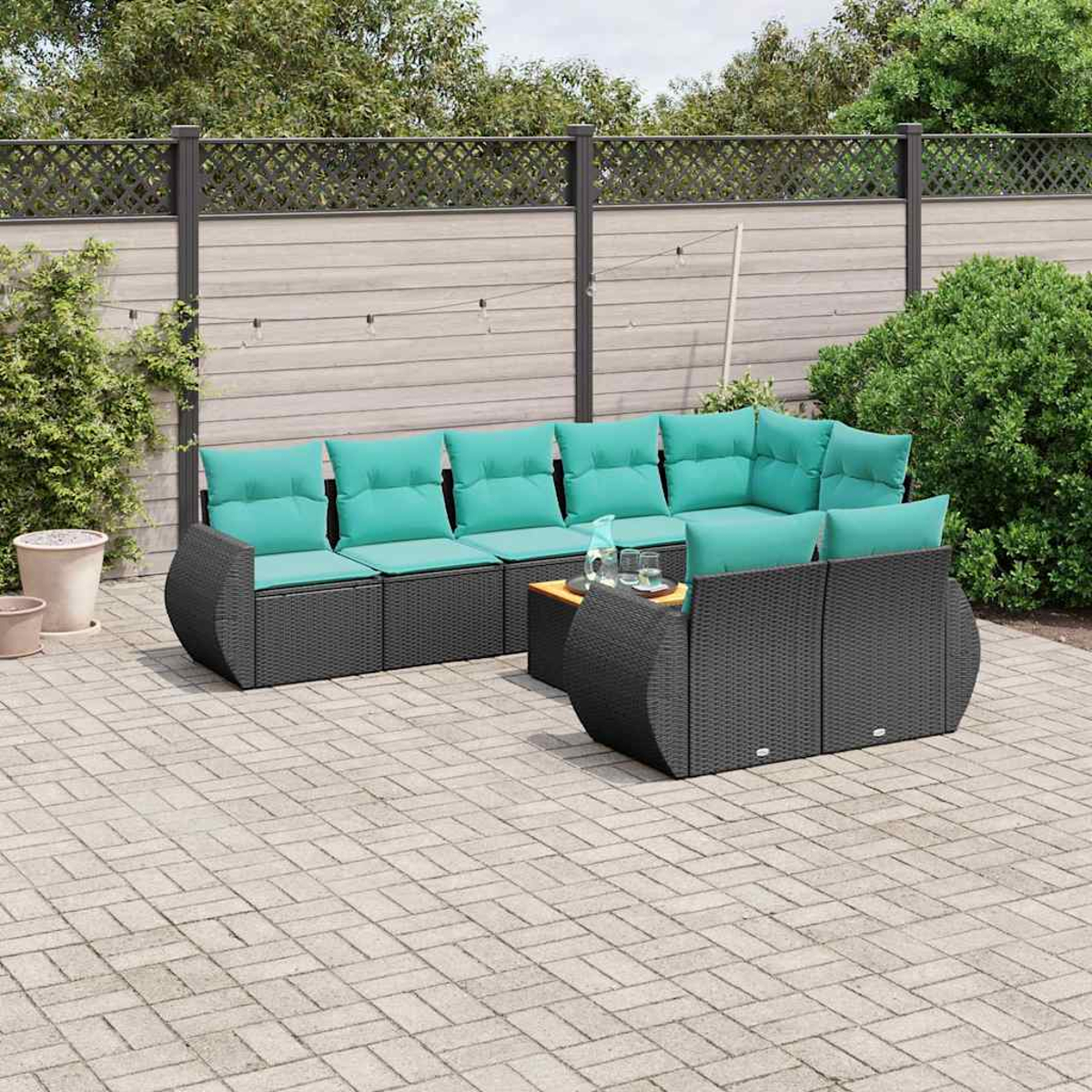 Dunkelgraue Rattan-Lounge mit türkisfarbenen Kissen und einem Holztisch im Freien.