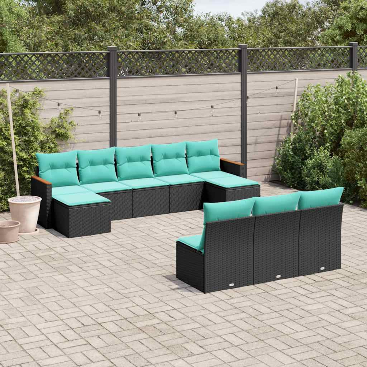 Dunkelgraue Polstermöbel mit türkisfarbenen Kissen auf einer gepflasterten Terrasse.