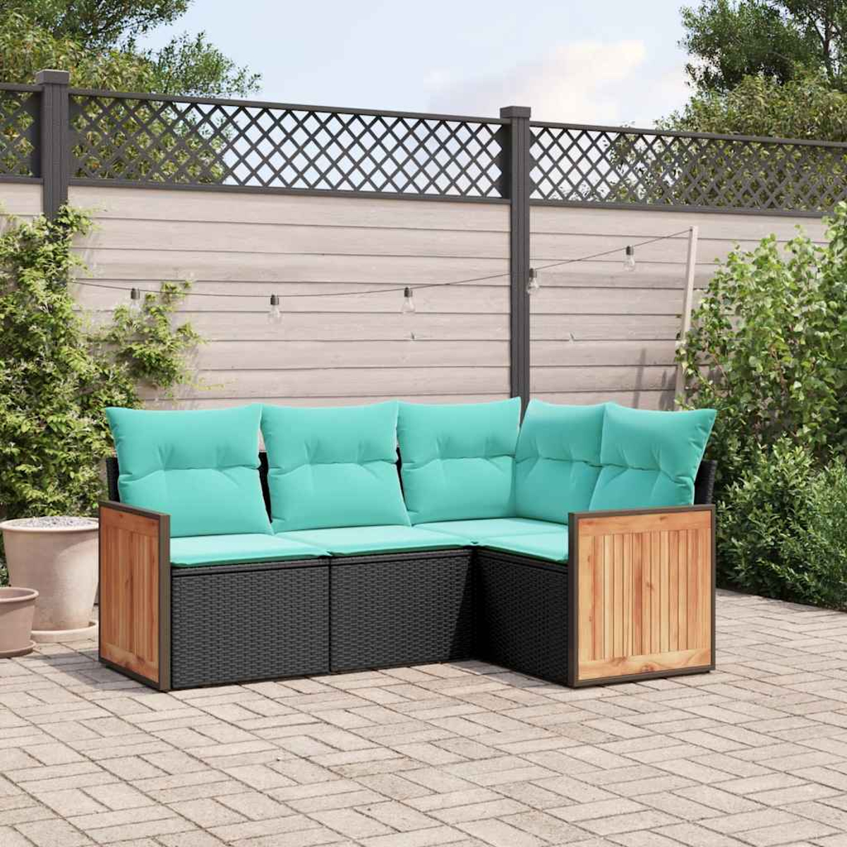 Ein schwarzes Rattan-Ecksofa mit türkisfarbenen Kissen steht auf einer gepflasterten Terrasse.
