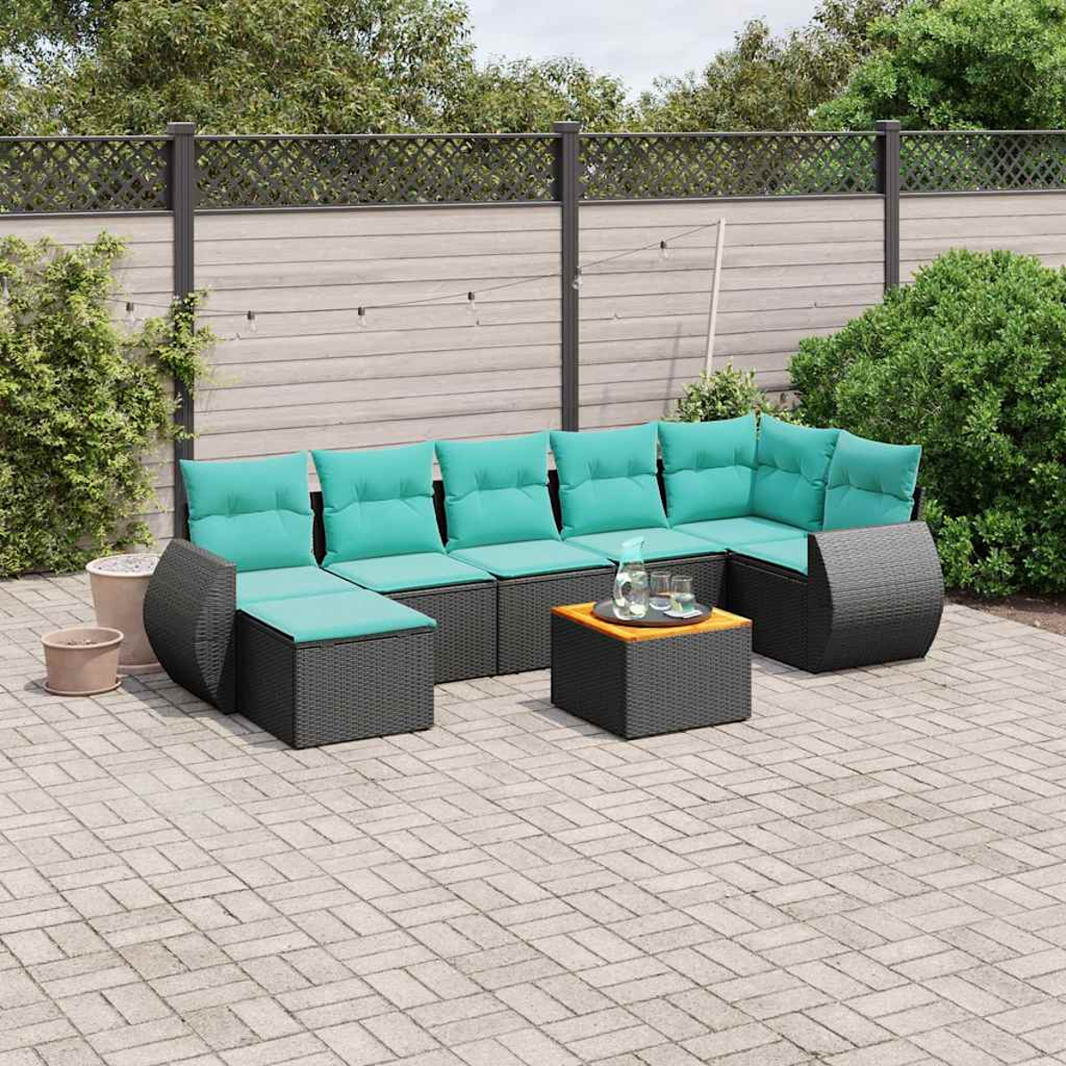 Ein moderner Gartenlounge-Sitzbereich mit schwarzen Rattansofas und türkisfarbenen Kissen.