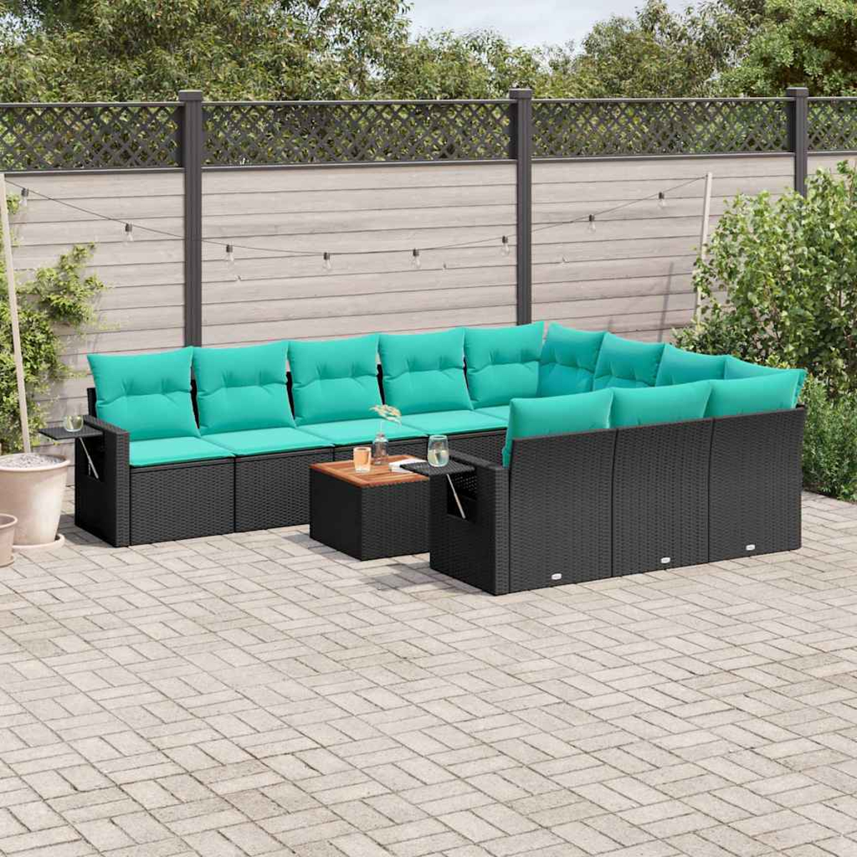 Ein schwarzes Rattan-Sofa mit türkisfarbenen Kissen, ein Beistelltisch mit Getränken.