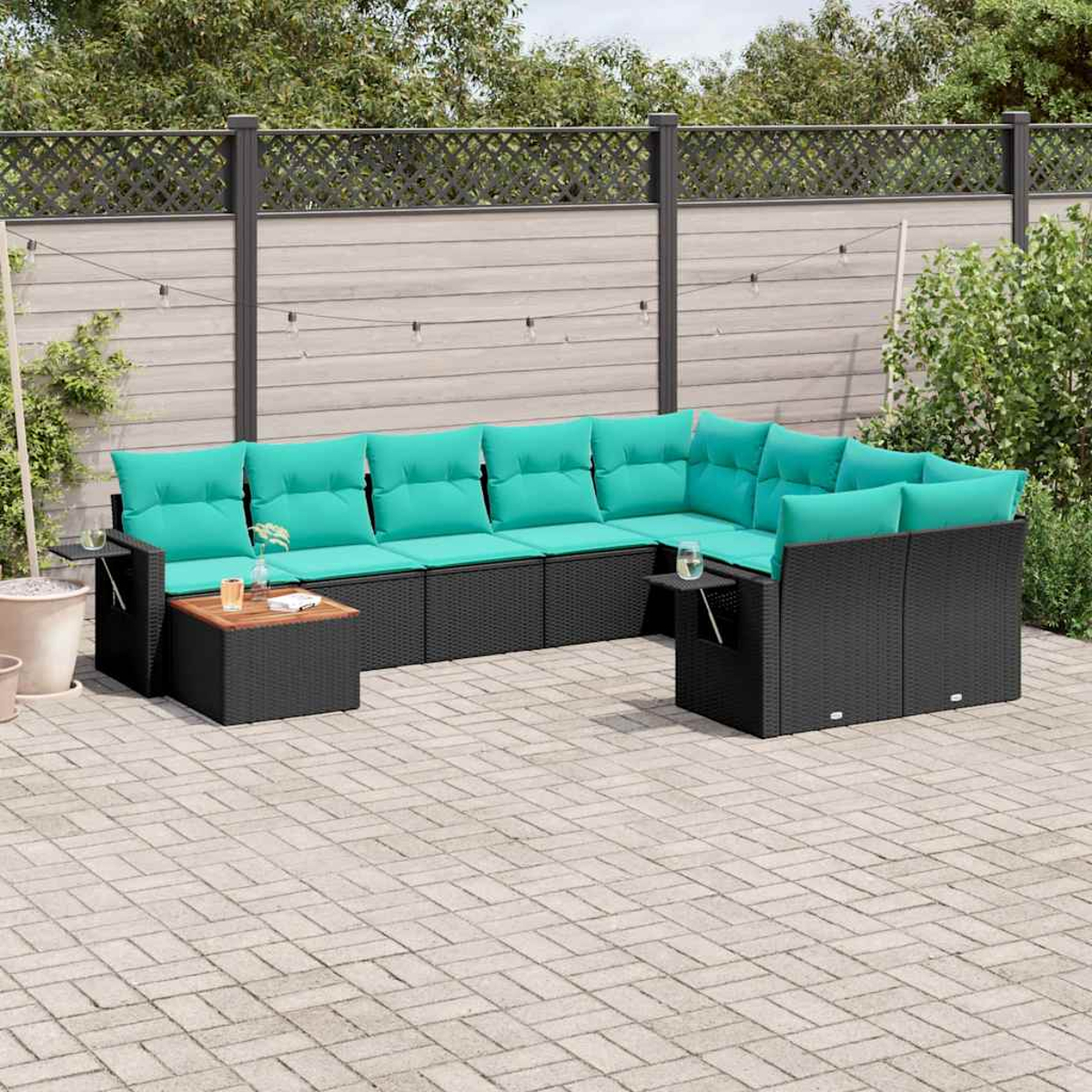 Ein schwarzes Lounge-Set mit türkisfarbenen Kissen auf einer gepflasterten Terrasse.
