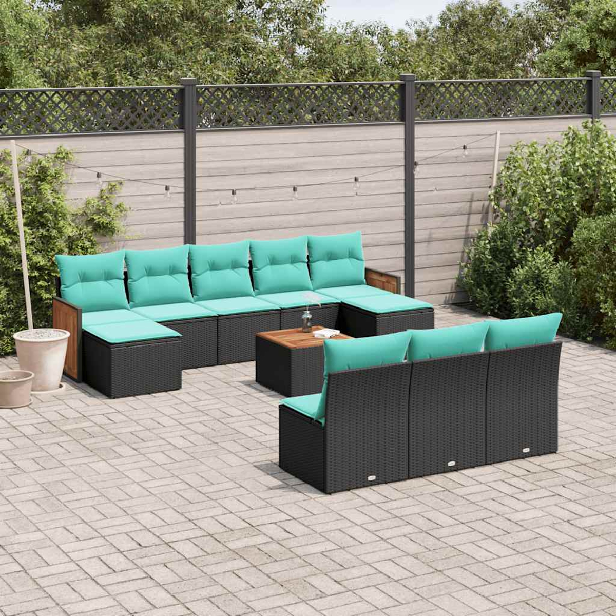 Dunkelgraue Rattan-Gartenmöbel mit türkisfarbenen Kissen und Holztisch auf einem Steinpflaster.