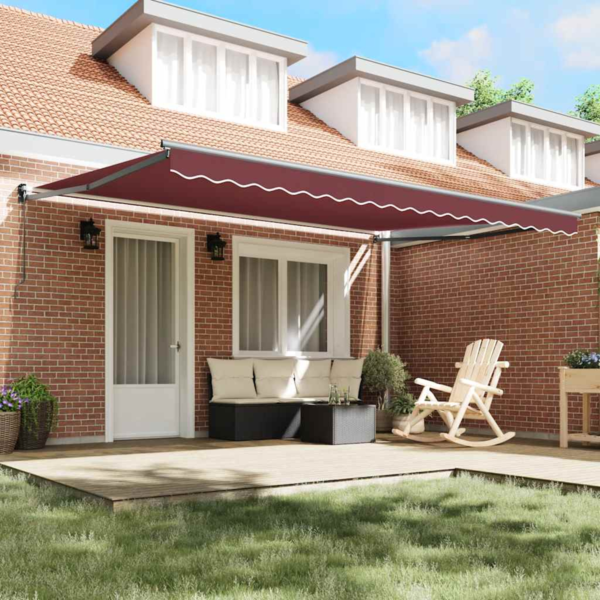 Una tenda da sole color vinaccia copre un patio in legno con mobili davanti a una casa di mattoni.