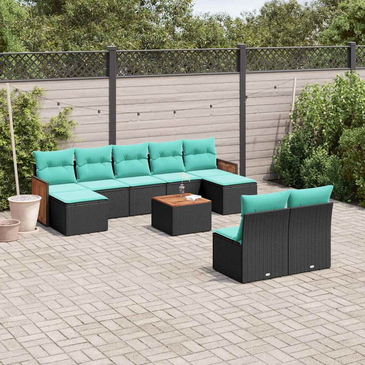 Gartenlounge mit schwarzen Rattanstühlen, türkisfarbenen Kissen und Holztisch.