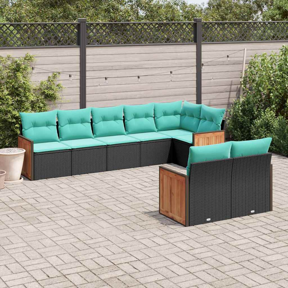 L-förmige Gartenlounge mit türkisfarbenen Kissen auf schwarzem Rattangeflecht und Holzdetails.