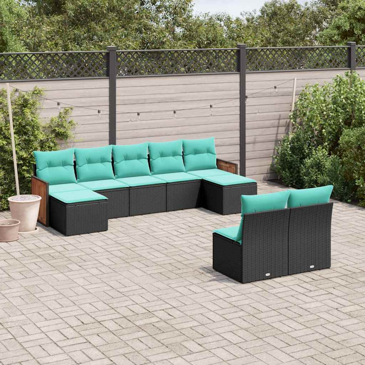 Gartenmöbel-Set mit schwarzen Rattan-Modulen und türkisfarbenen Kissen auf einer Pflastersteinterrasse.