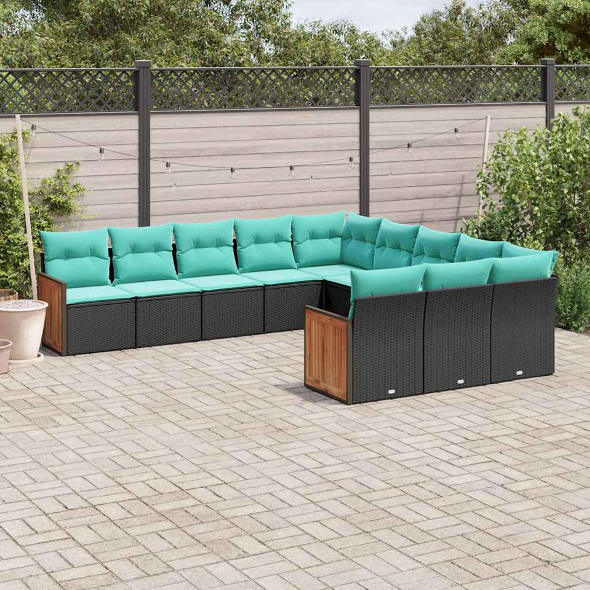 Dunkelgraue Lounge-Ecke mit türkisfarbenen Kissen und Holzakzenten auf einer gepflasterten Terrasse.