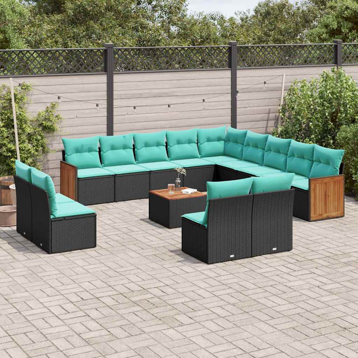 Ein großes, modulares Gartensofa aus schwarzem Rattan mit türkisfarbenen Kissen.