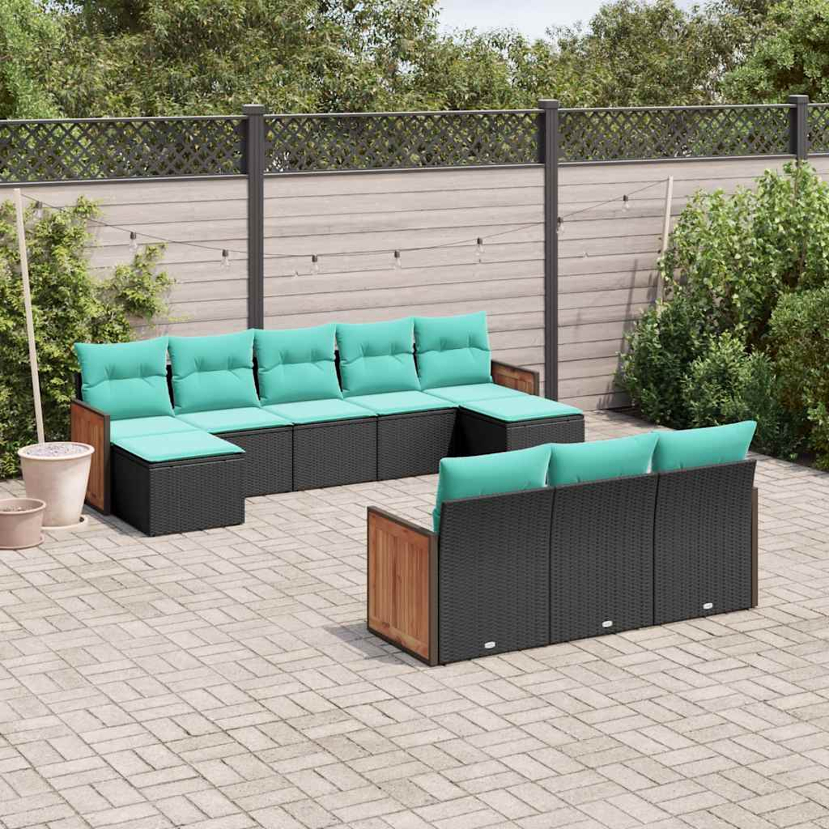 Gartenmöbel-Set aus schwarzem Rattan mit hellgrünen Kissen auf einer gepflasterten Terrasse.