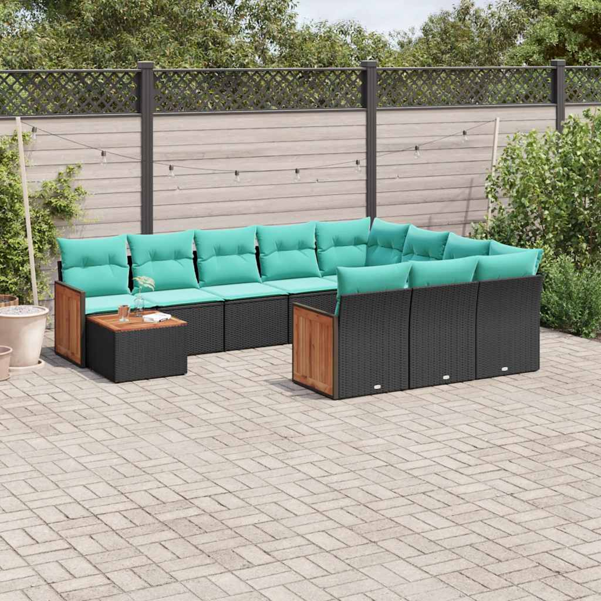 Ein dunkles Rattan-Ecksofa mit türkisen Kissen auf einem gepflasterten Hof.