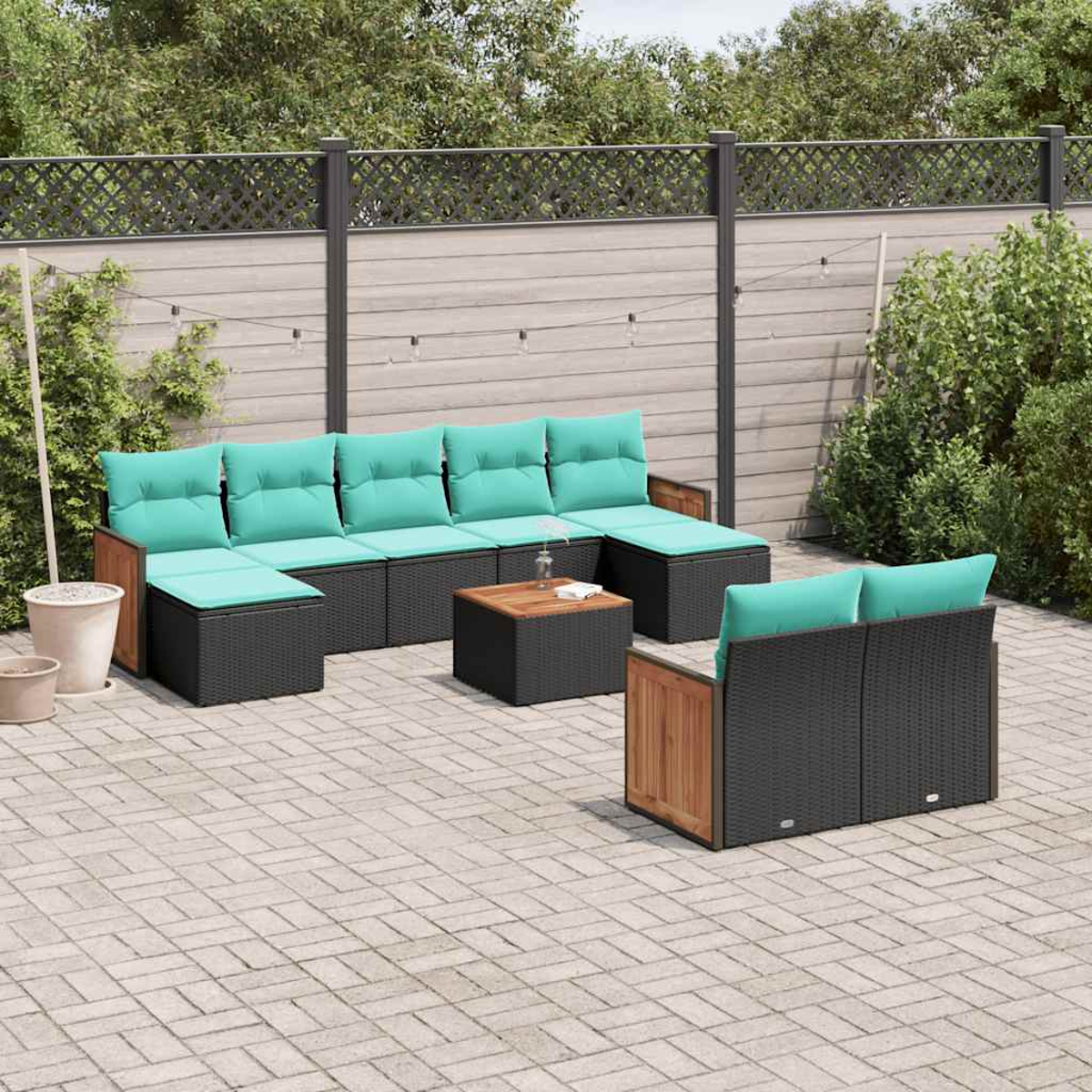 Gartenmöbel-Set mit schwarzen Rattan-Modulen, türkisen Kissen und Holzakzenten auf gepflastertem Hof.