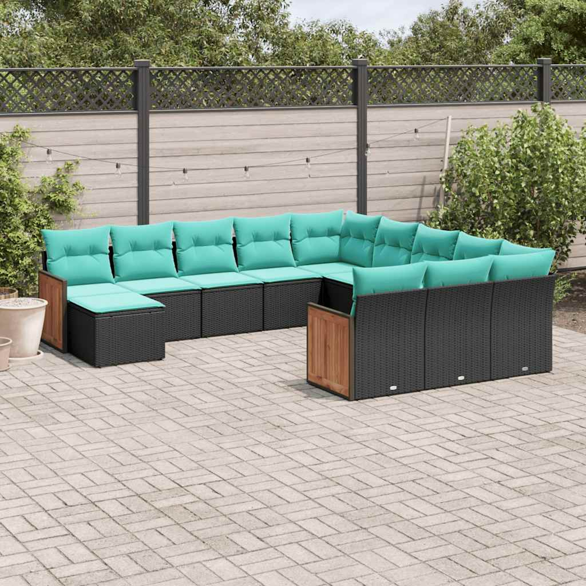 Ein modulares Outdoor-Sofa mit tealfarbenen Kissen auf einer gepflasterten Terrasse.