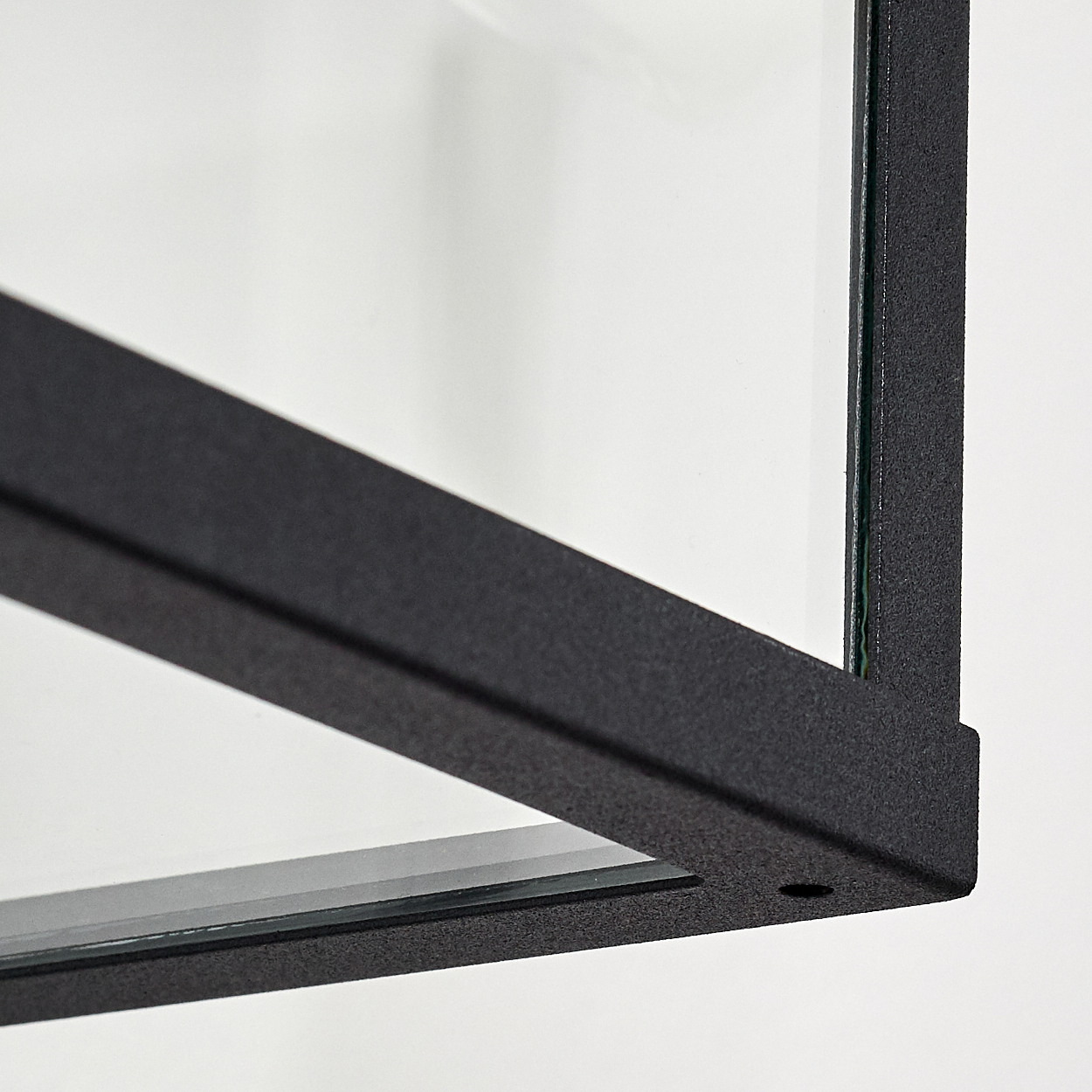 Nahaufnahme eines schwarzen Metallrahmens mit Glas vor weißem Hintergrund.