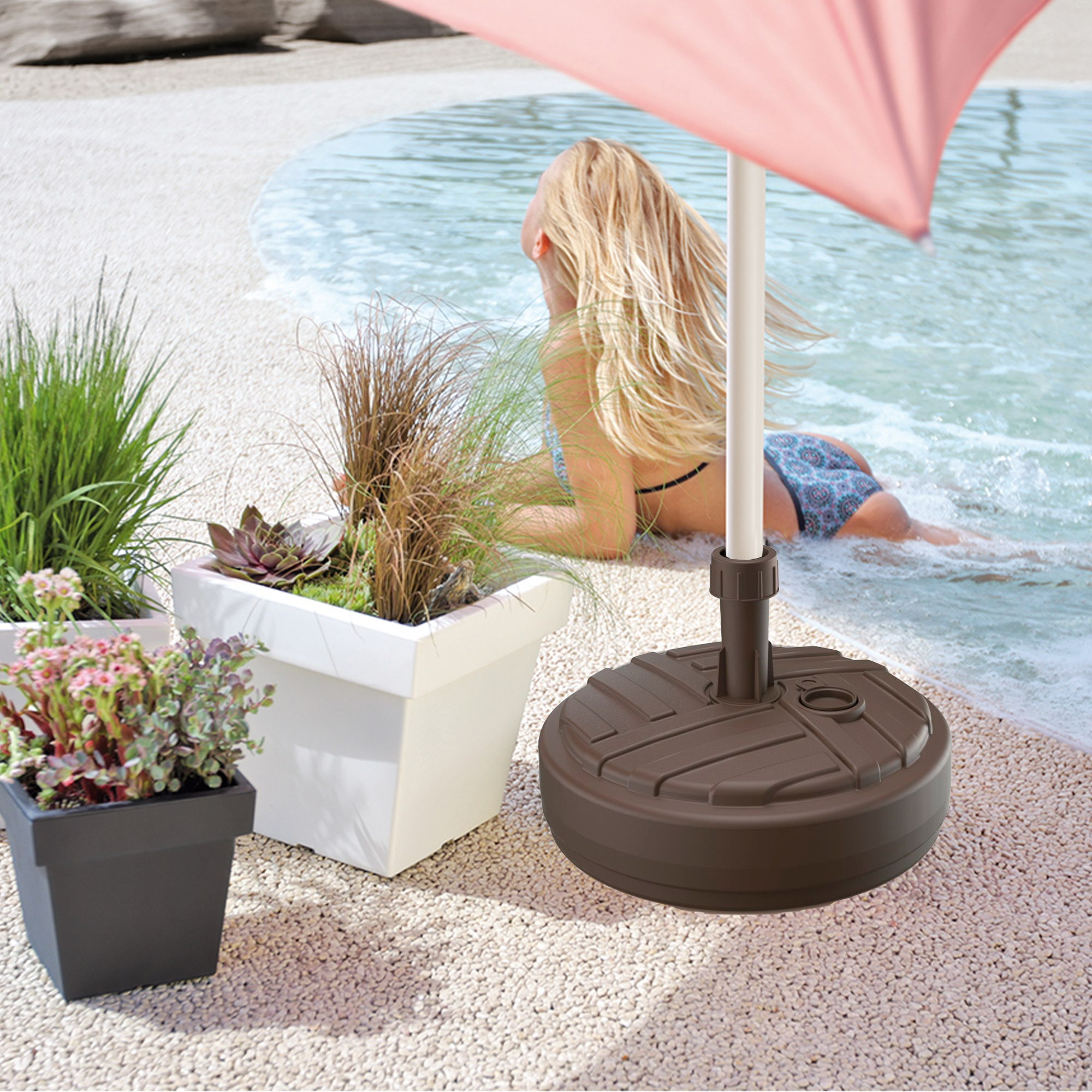 Mujer en bikini yace junto a la piscina. Macetas y base de sombrilla en primer plano.