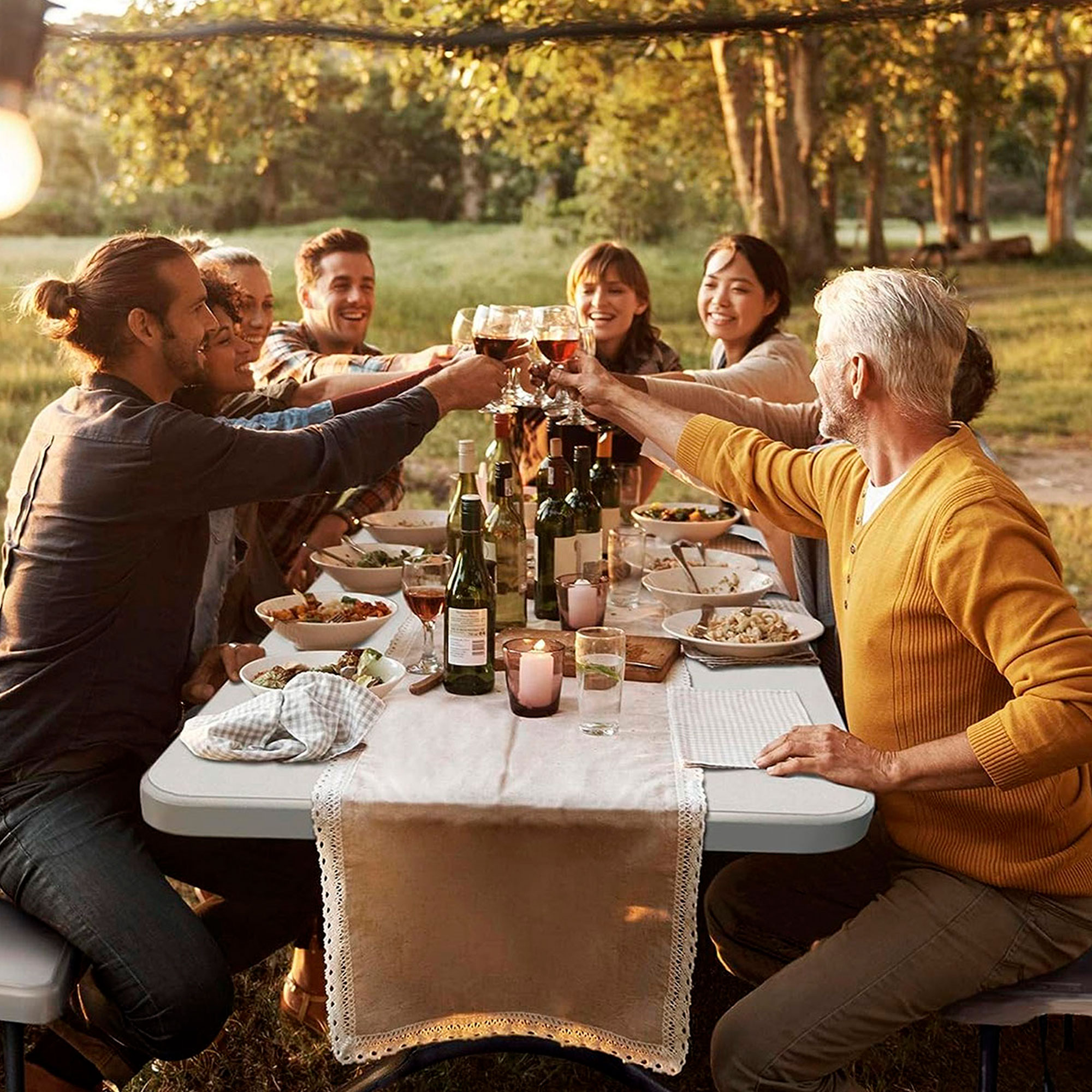 Personas brindan con copas de vino sentadas a una mesa al aire libre.