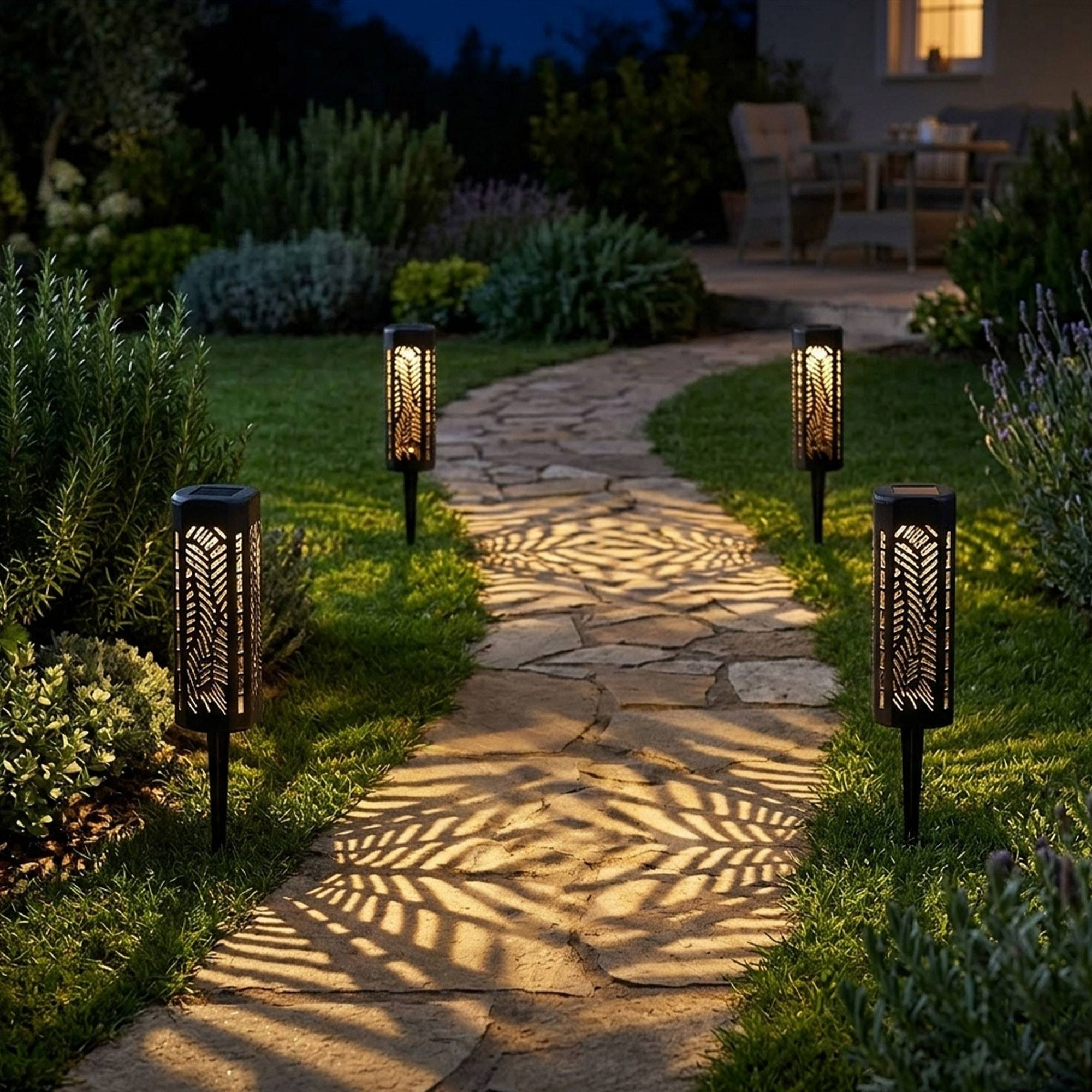 Camino de jardín iluminado con farolas solares que proyectan patrones.