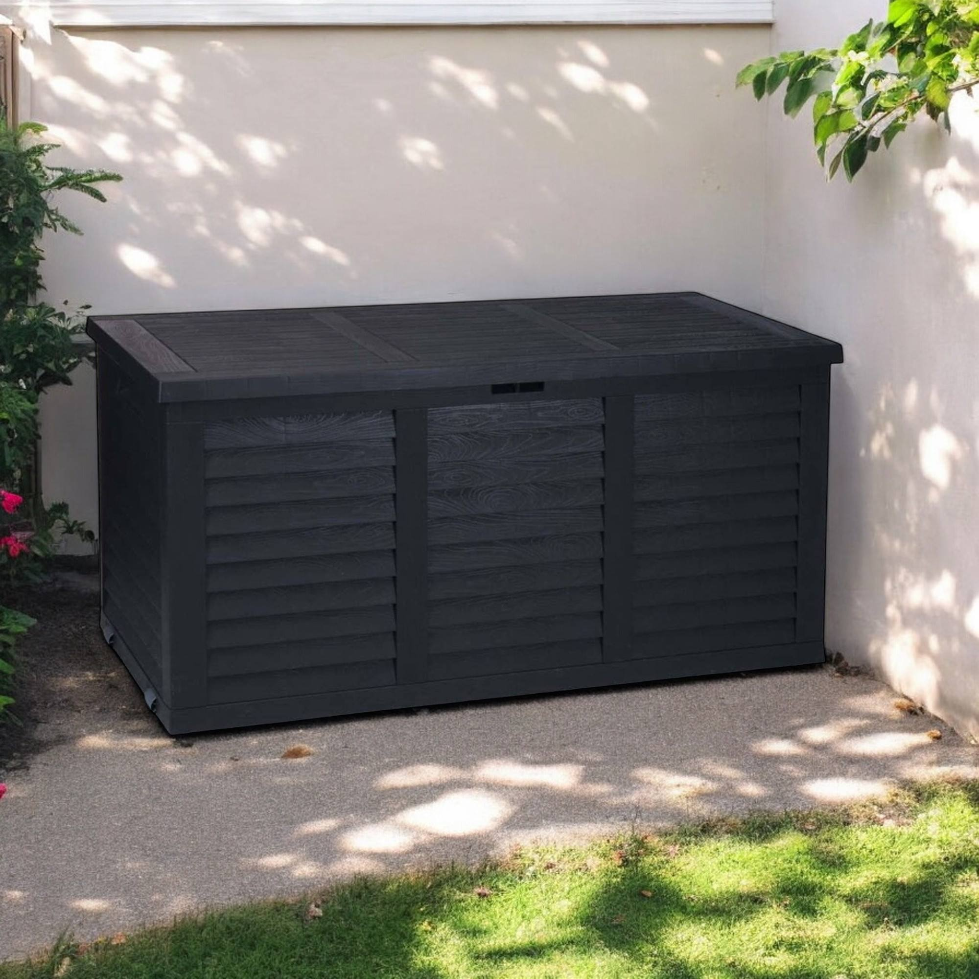 Caja de almacenamiento gris oscuro con diseño de lamas sobre un camino de grava.