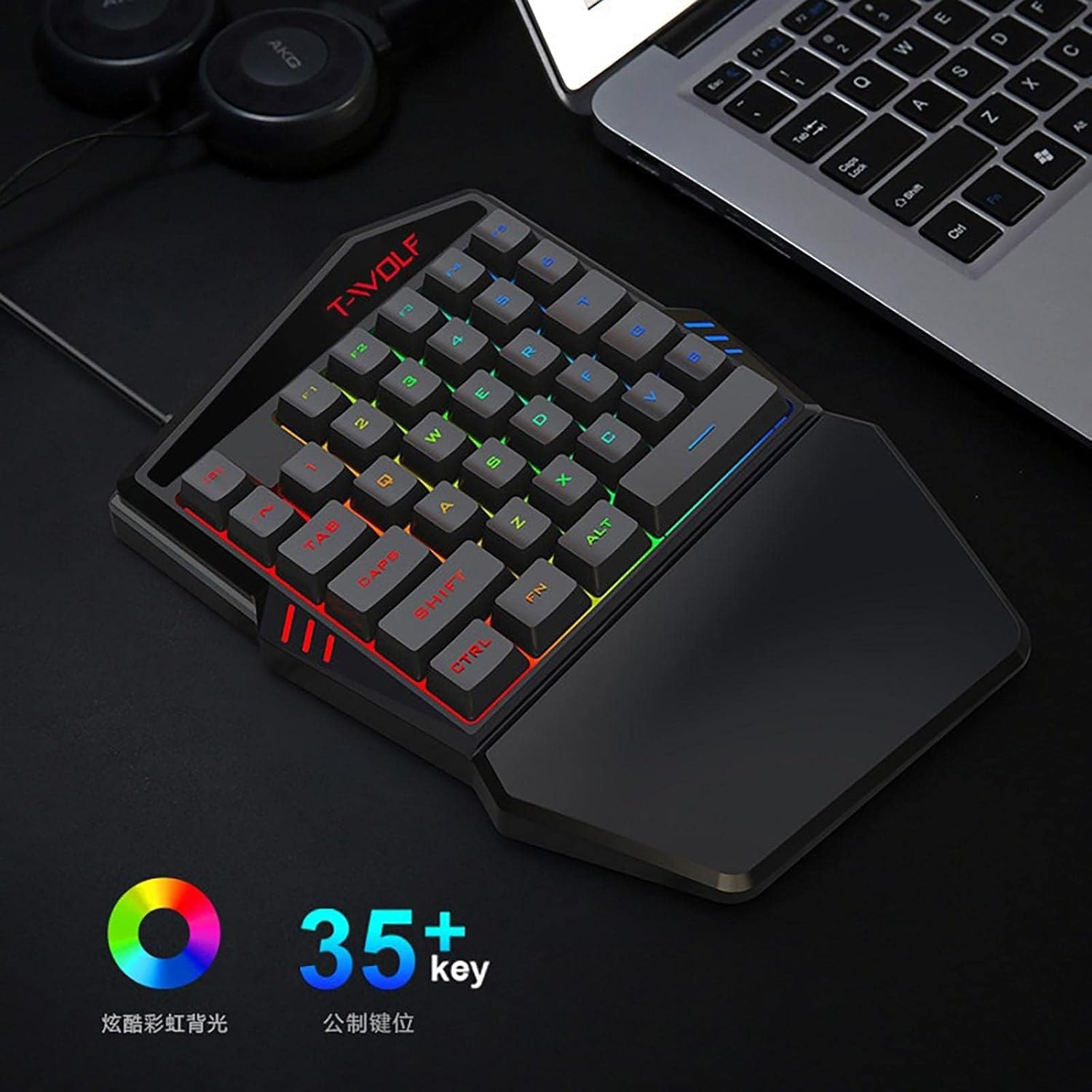 Gaming-Tastatur mit RGB-Beleuchtung und Handballenauflage neben einem Laptop.