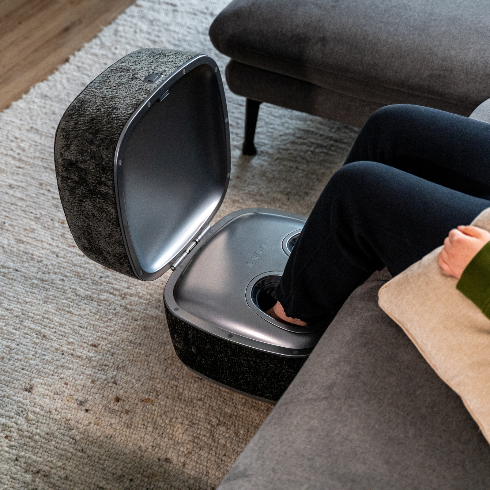 Eine Person sitzt auf einem Sofa und benutzt eine Fußmassagegerät.