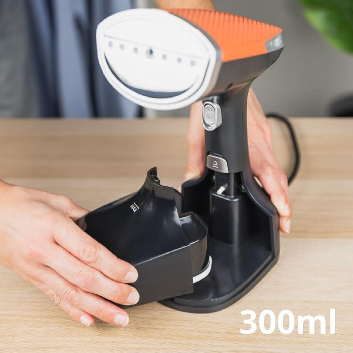 Mani agganciano un serbatoio dell'acqua nero a un vaporizzatore di tessuto portatile con parte superiore arancione.