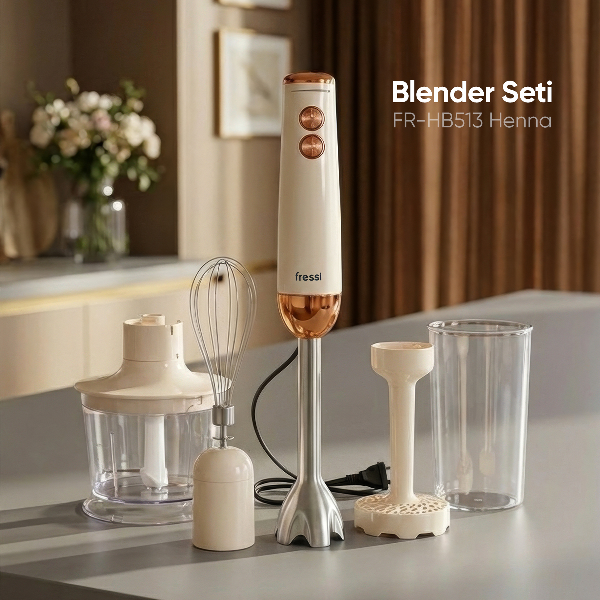 Bakır vurgulu krem rengi el blenderi ve aksesuarları masada.
