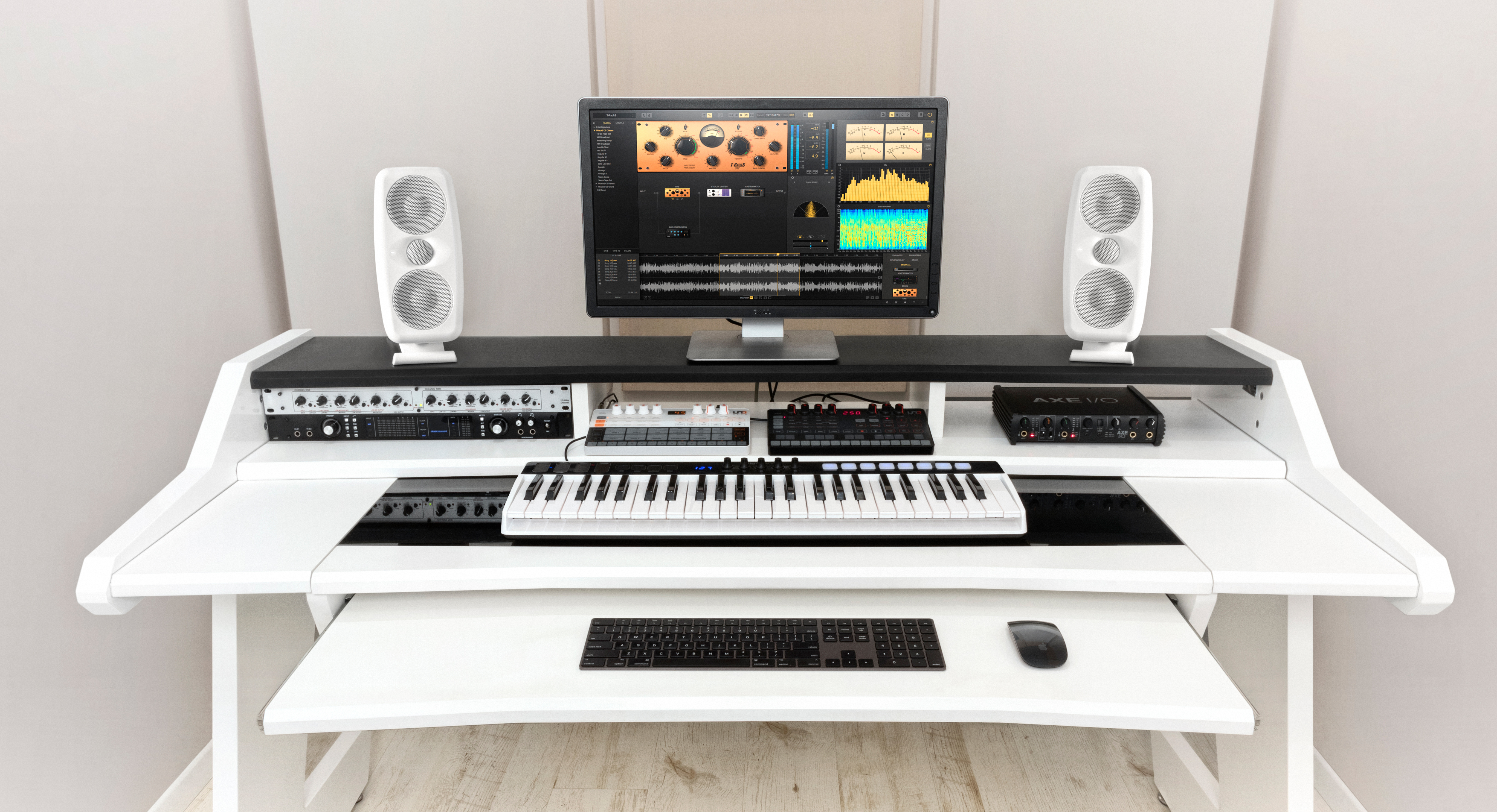 Een wit studiemeubel met monitor, toetsenbord, muis en audioapparatuur.