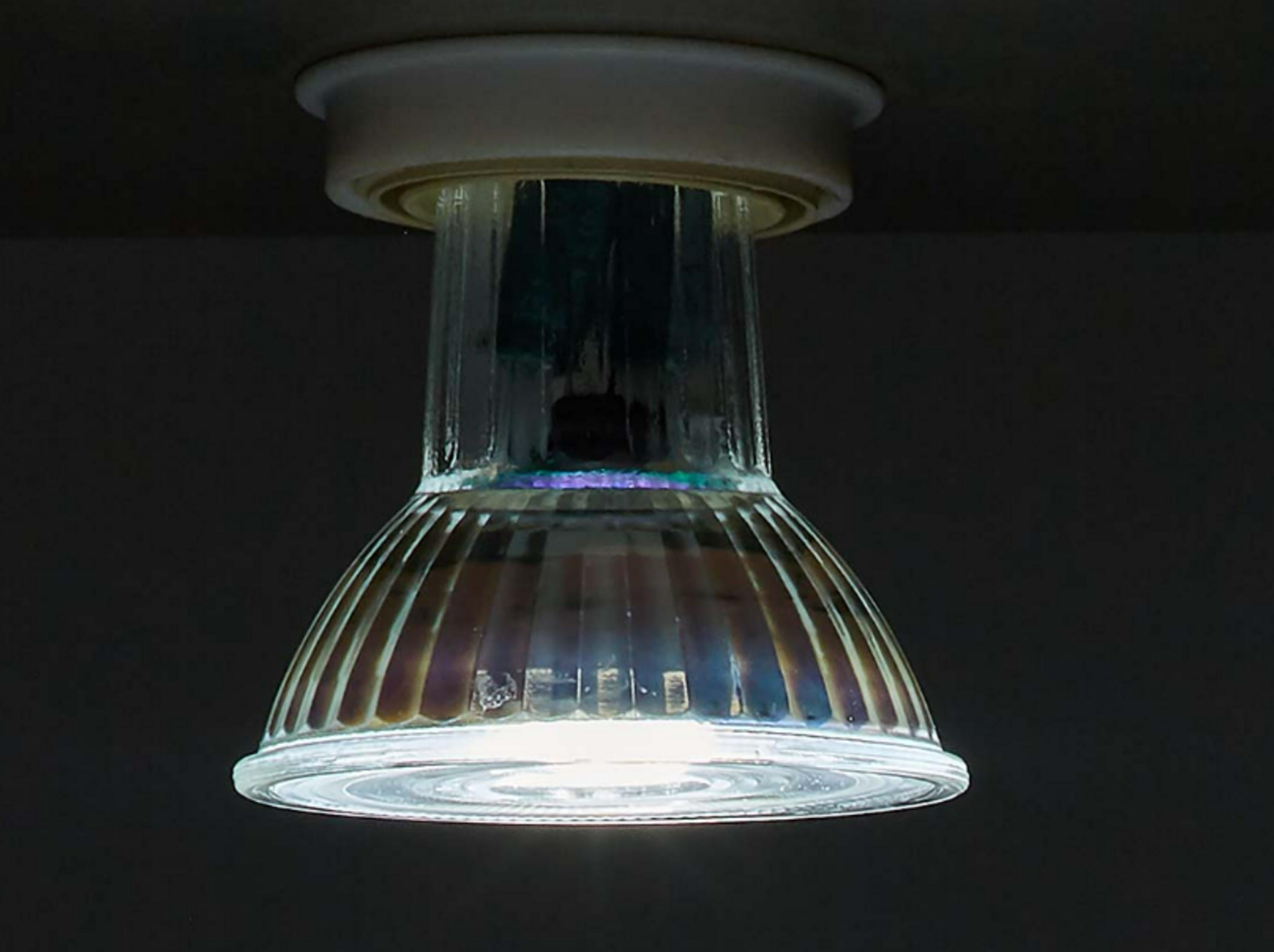 Eine Glühbirne mit geriffeltem Glas in einer Deckenleuchte, die Dunkelheit.