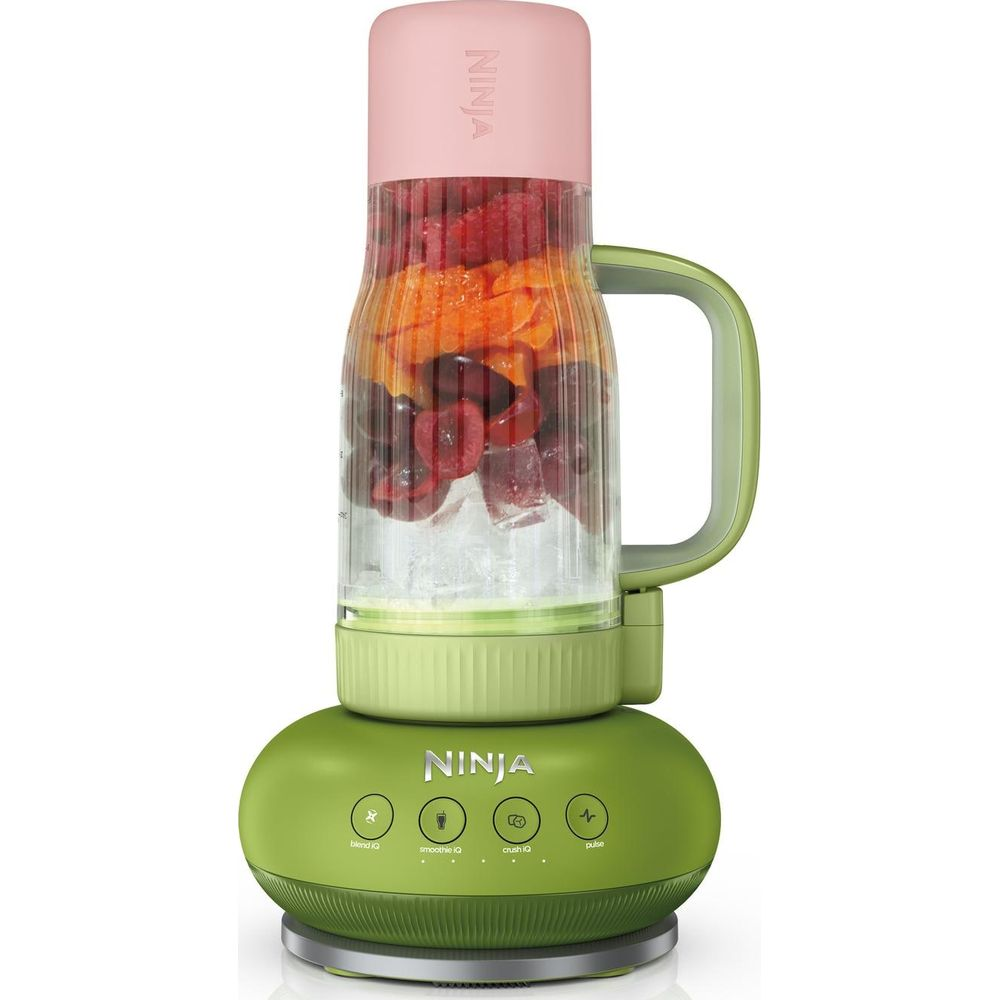 Ein grüner Ninja-Mixer mit rosa Deckel enthält Eis, Kirschen, Himbeeren und Orangenscheiben.