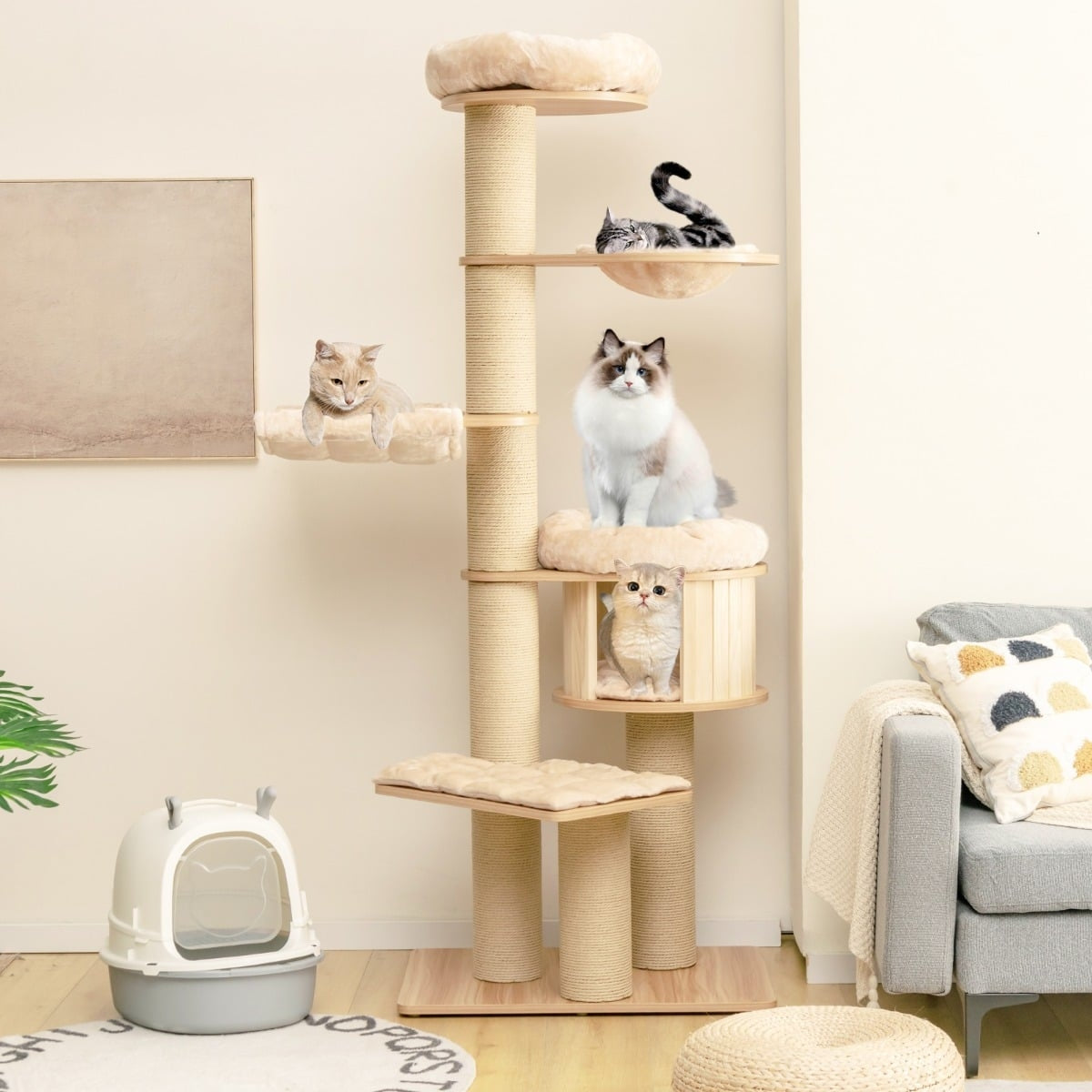 Four cats relax on a multi-level cat tree. A litter box is nearby.