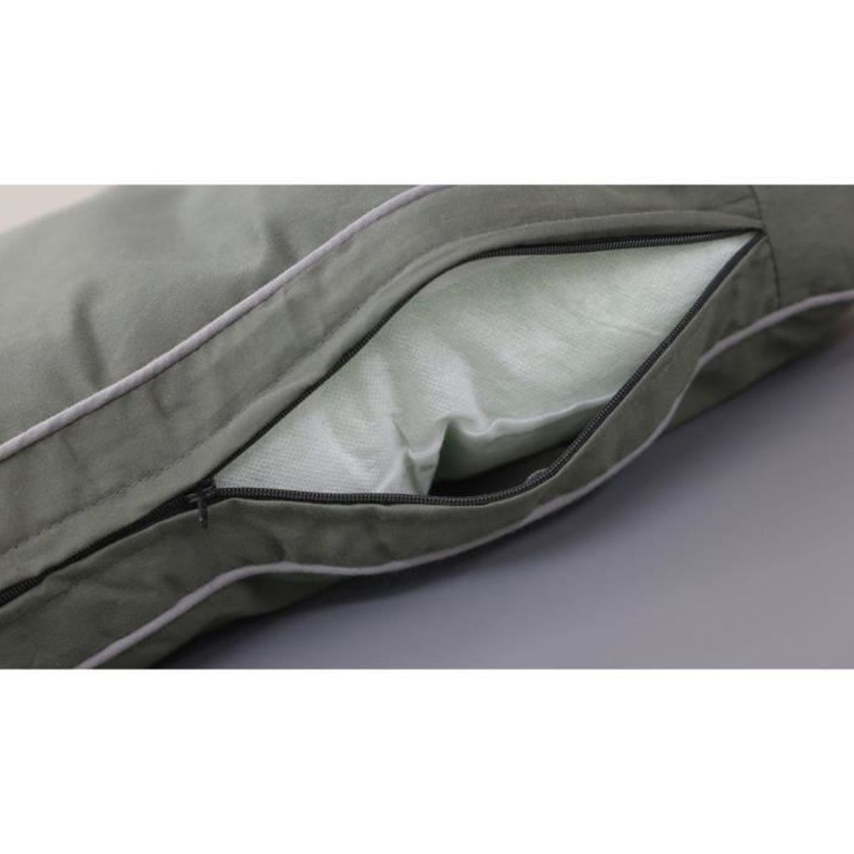 A close-up of a green pillow with a partially opened zipper, revealing a lighter green inner lining.