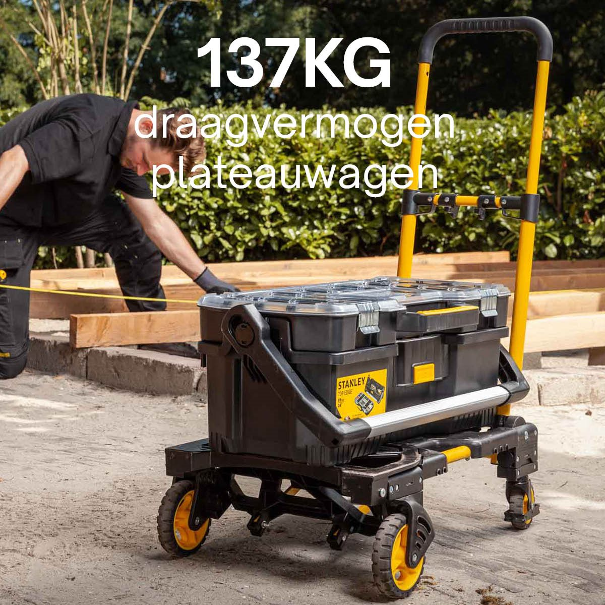 A man in black clothes with a trolley full of toolboxes.