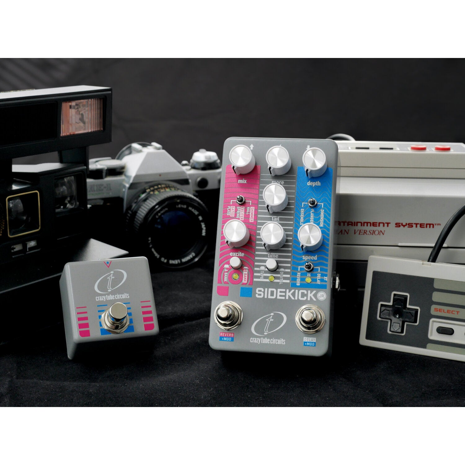 A Polaroid camera, an SLR camera, and two guitar pedals sit on black fabric.