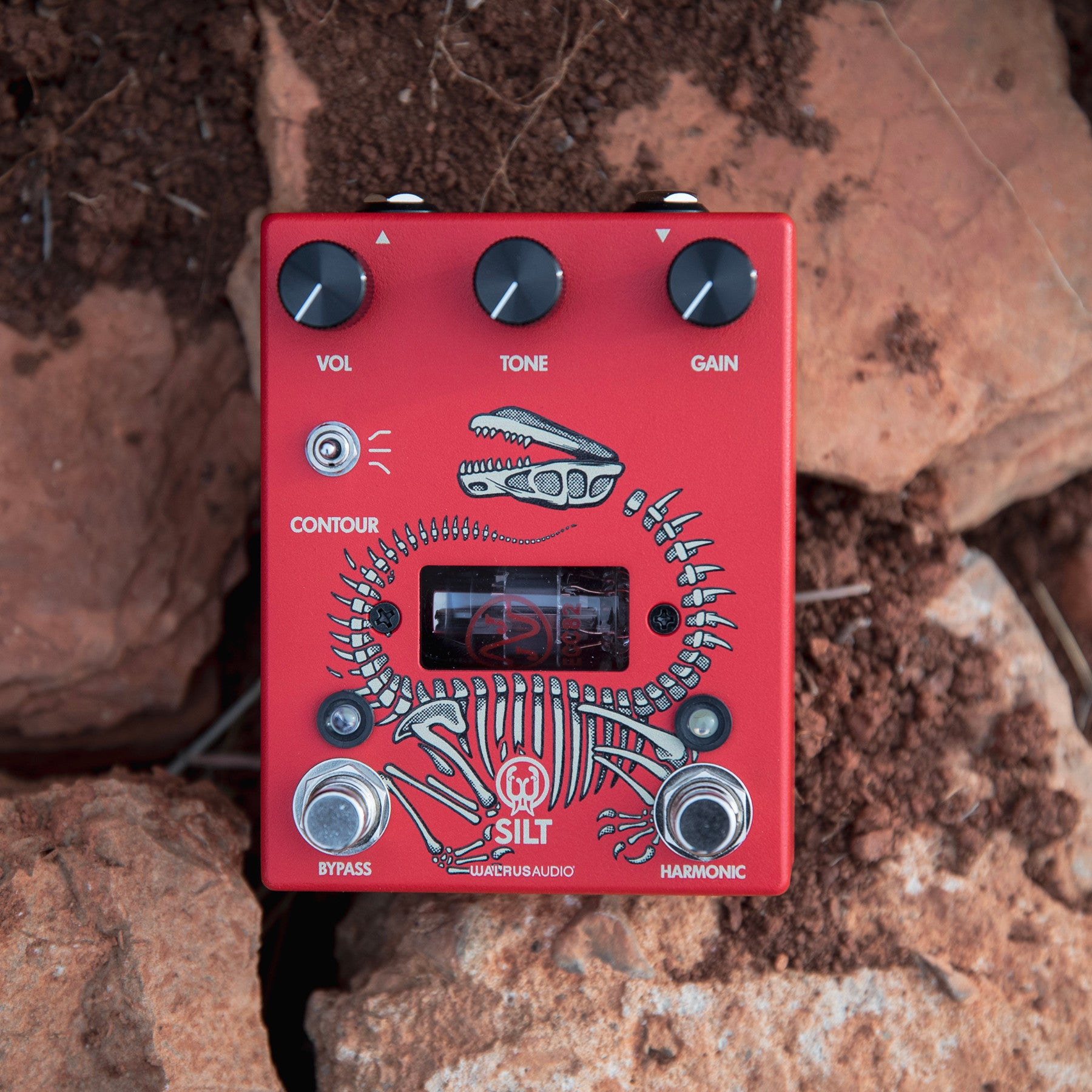 Red guitar pedal with skeleton art, knobs for Vol, Tone, Gain. Tube visible.