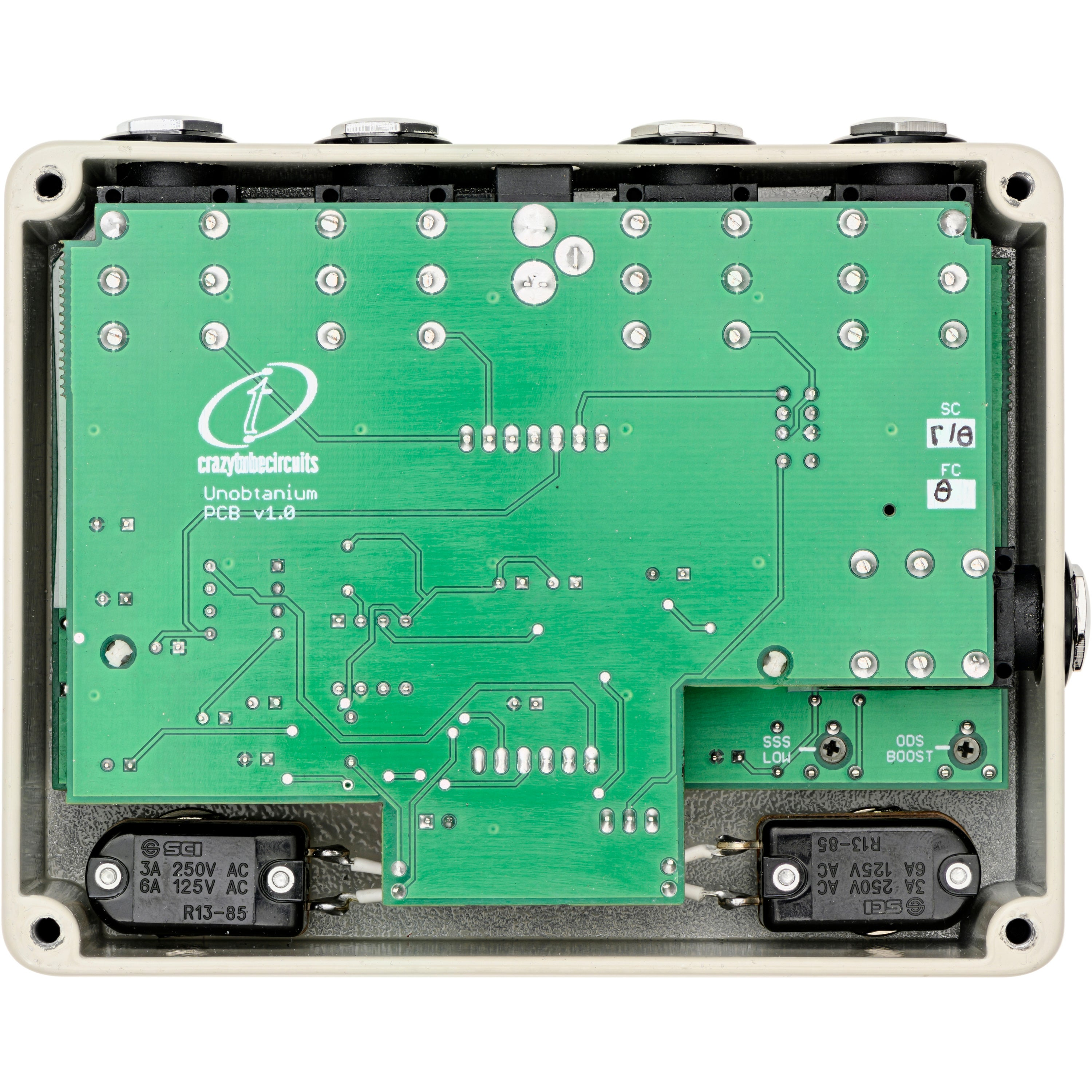 Green circuit board with labels, switches, and connectors inside a housing.
