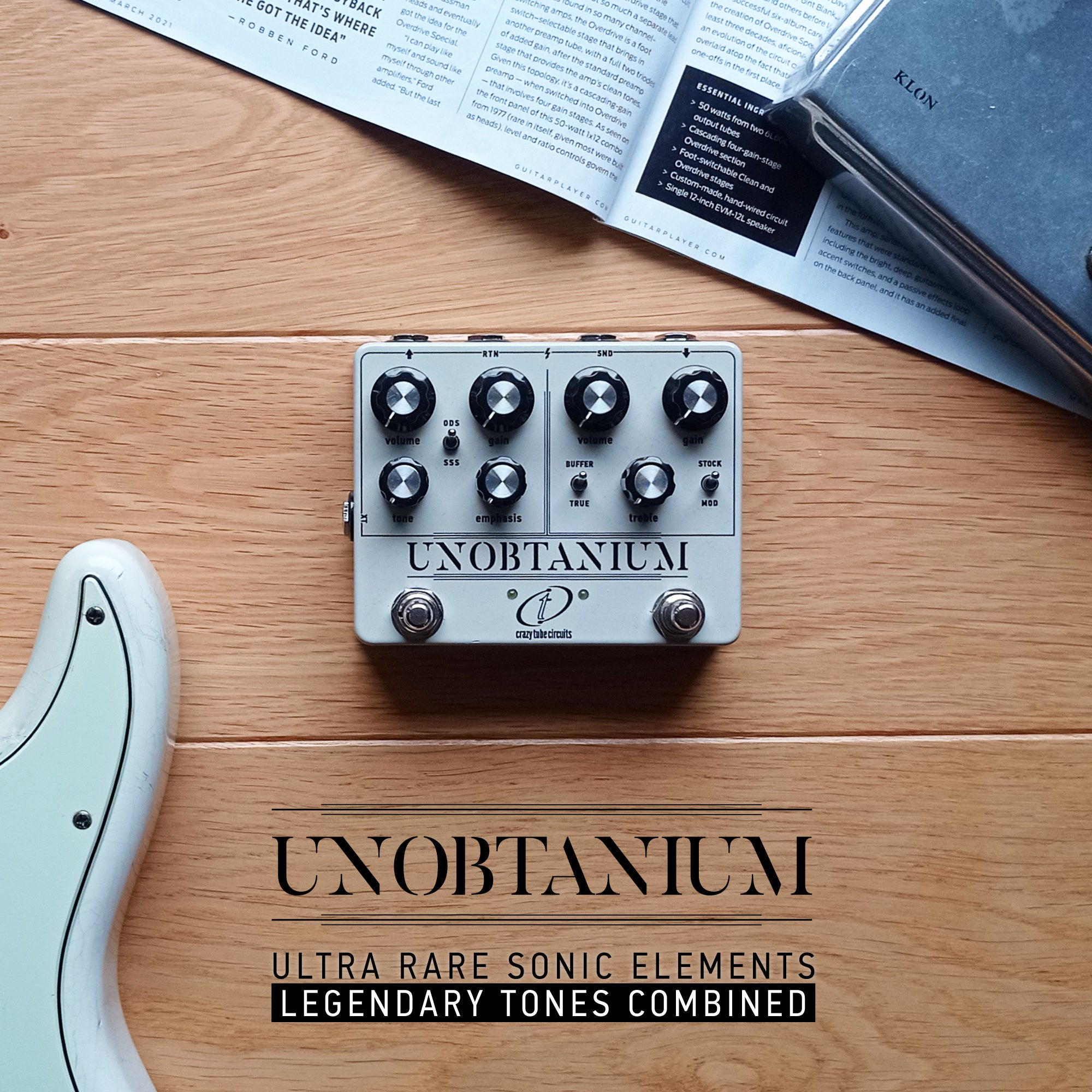 A white guitar pedal named Unobtanium sits on a wooden surface, next to a guitar.