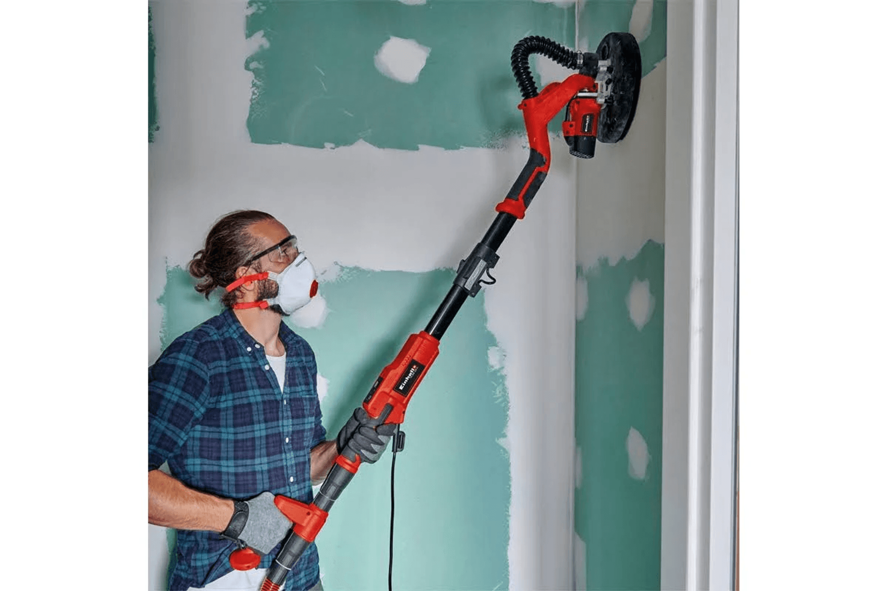 Mann mit Maske schleift Wand mit langem Gerät.