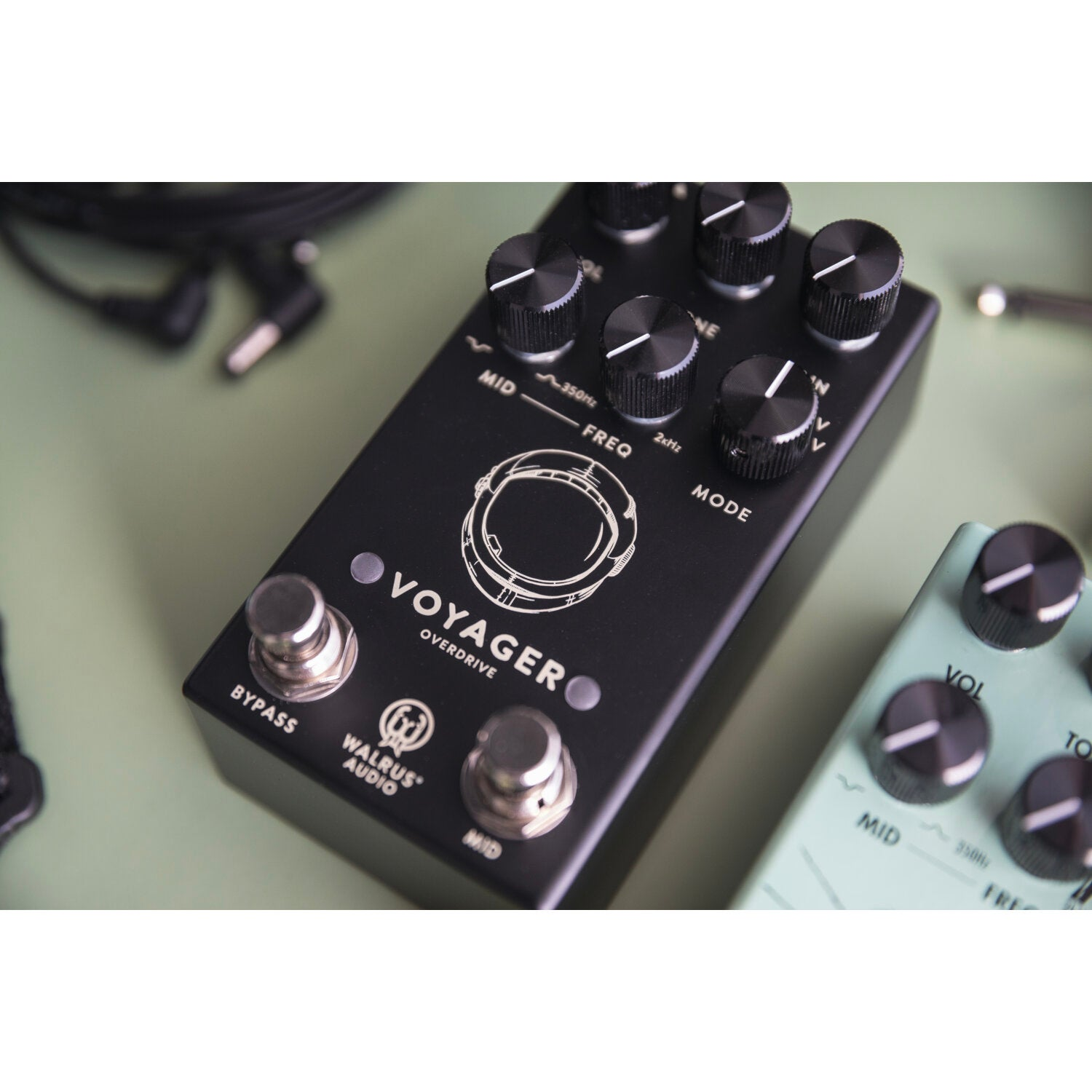Black Walrus Audio Voyager overdrive pedal and a teal pedal with knobs on a green surface.