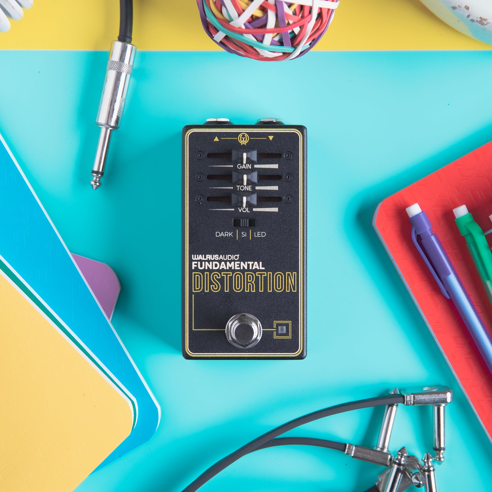 A Walrus Audio distortion pedal lies on a turquoise surface.