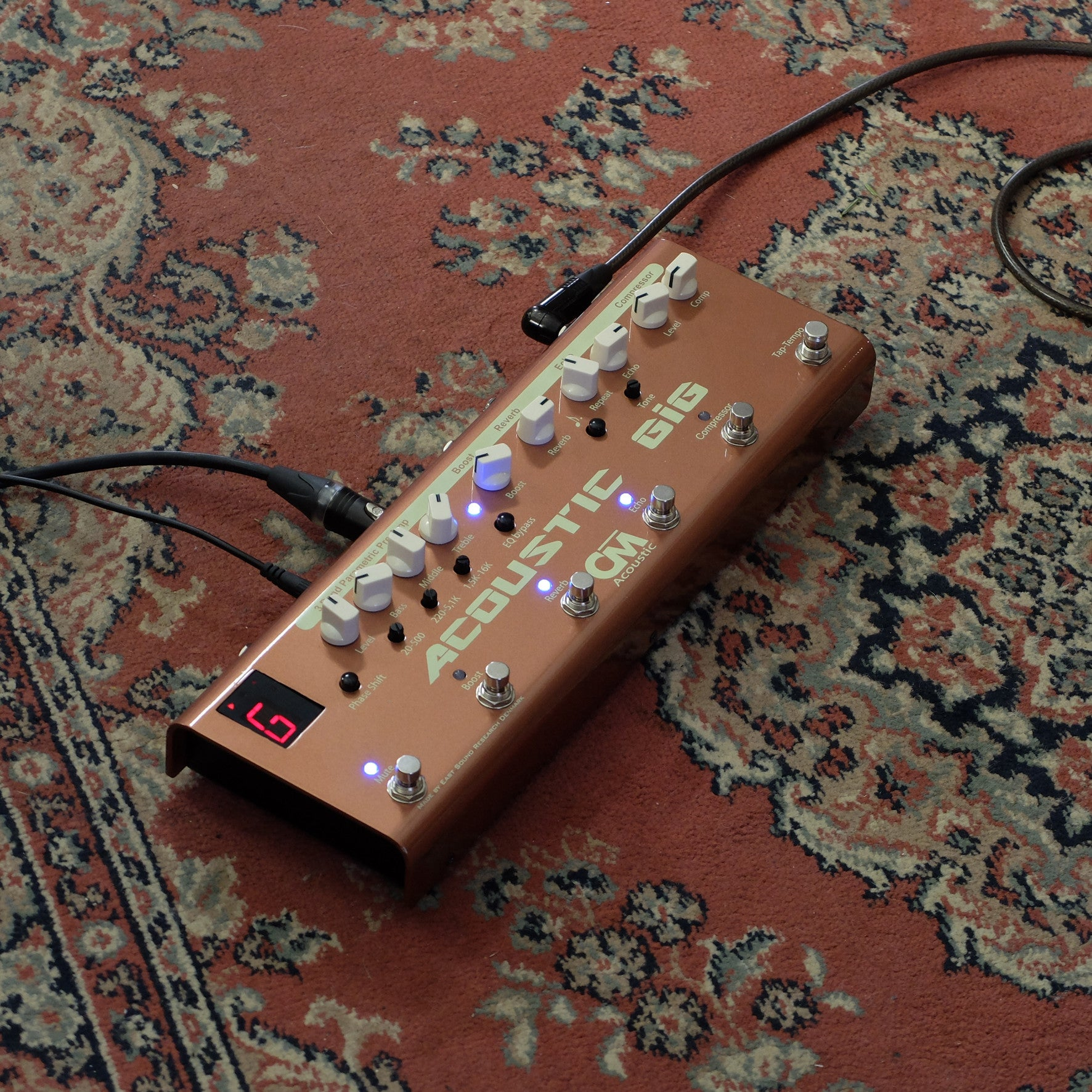 A copper guitar effects pedal with white knobs on a carpet.