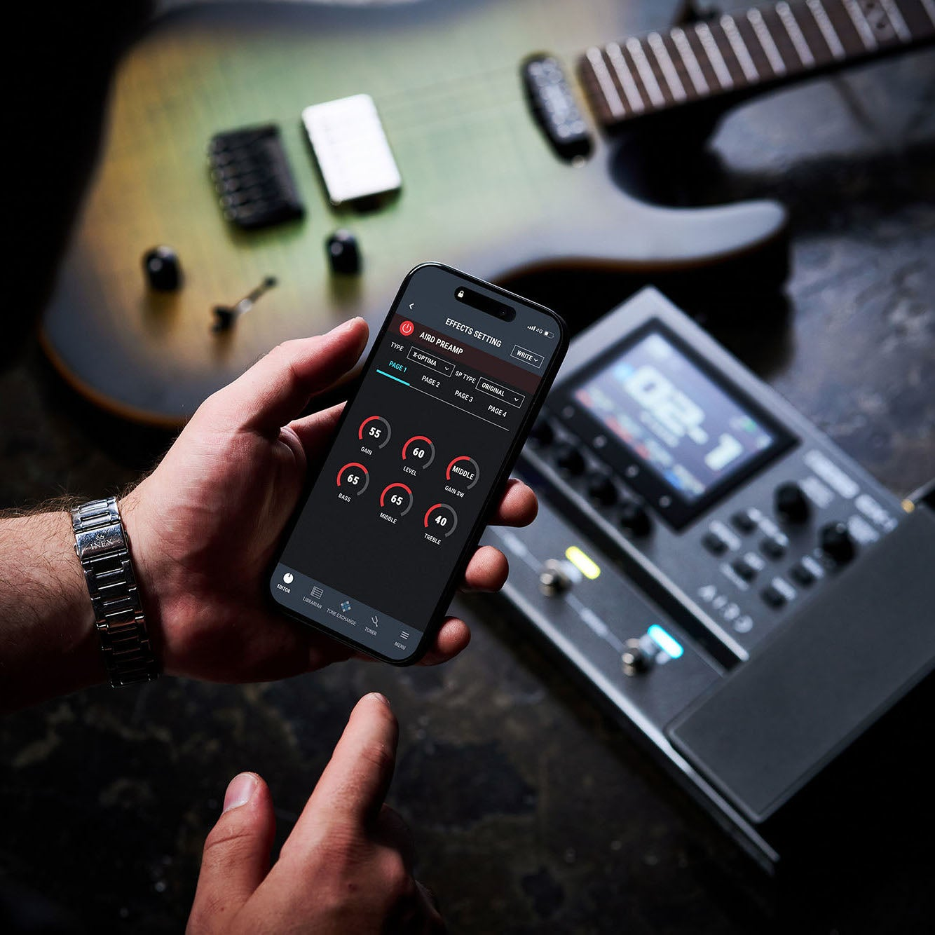 Man holds smartphone with guitar effects settings, guitar in background.