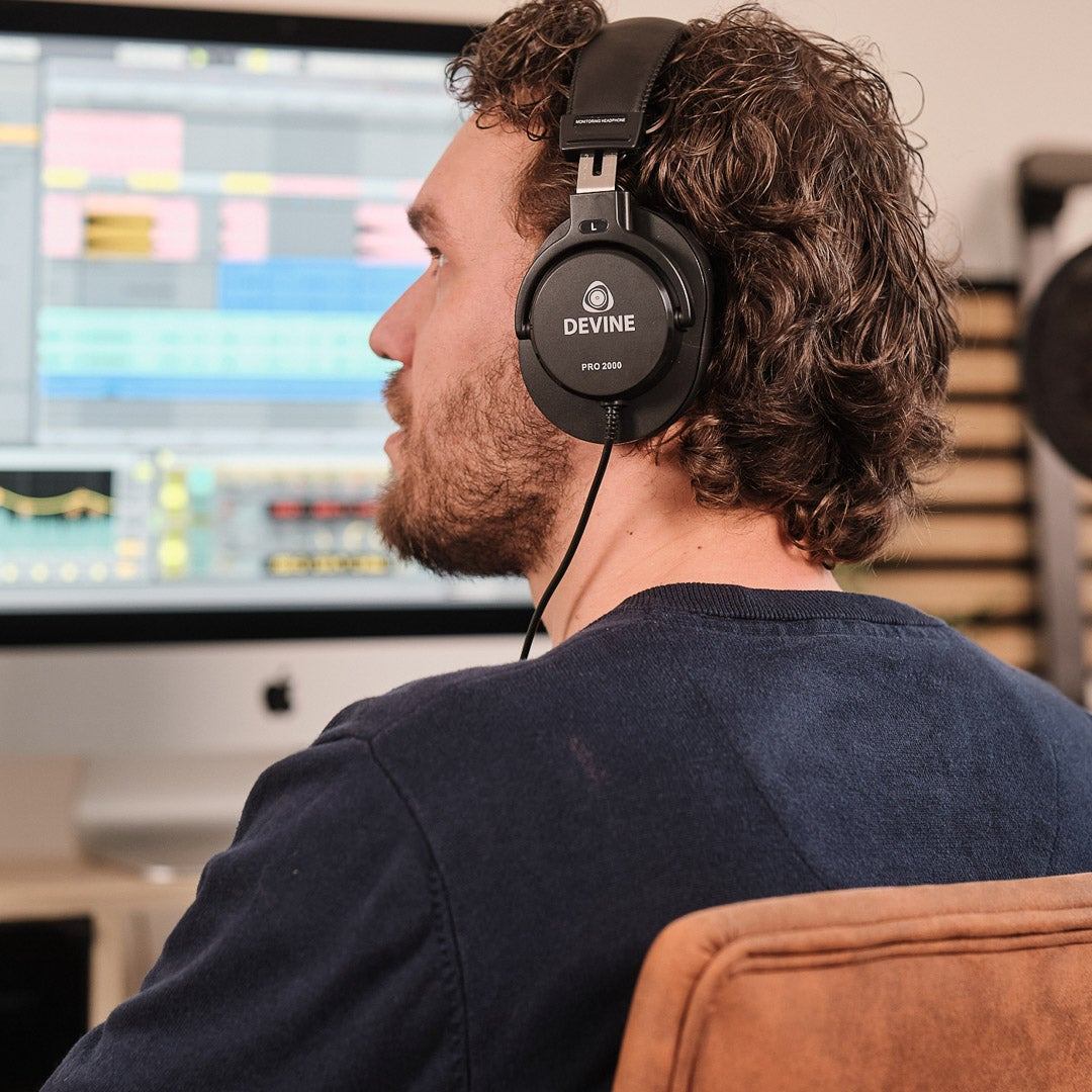 Man met koptelefoon voor computerscherm met muzieksoftware.