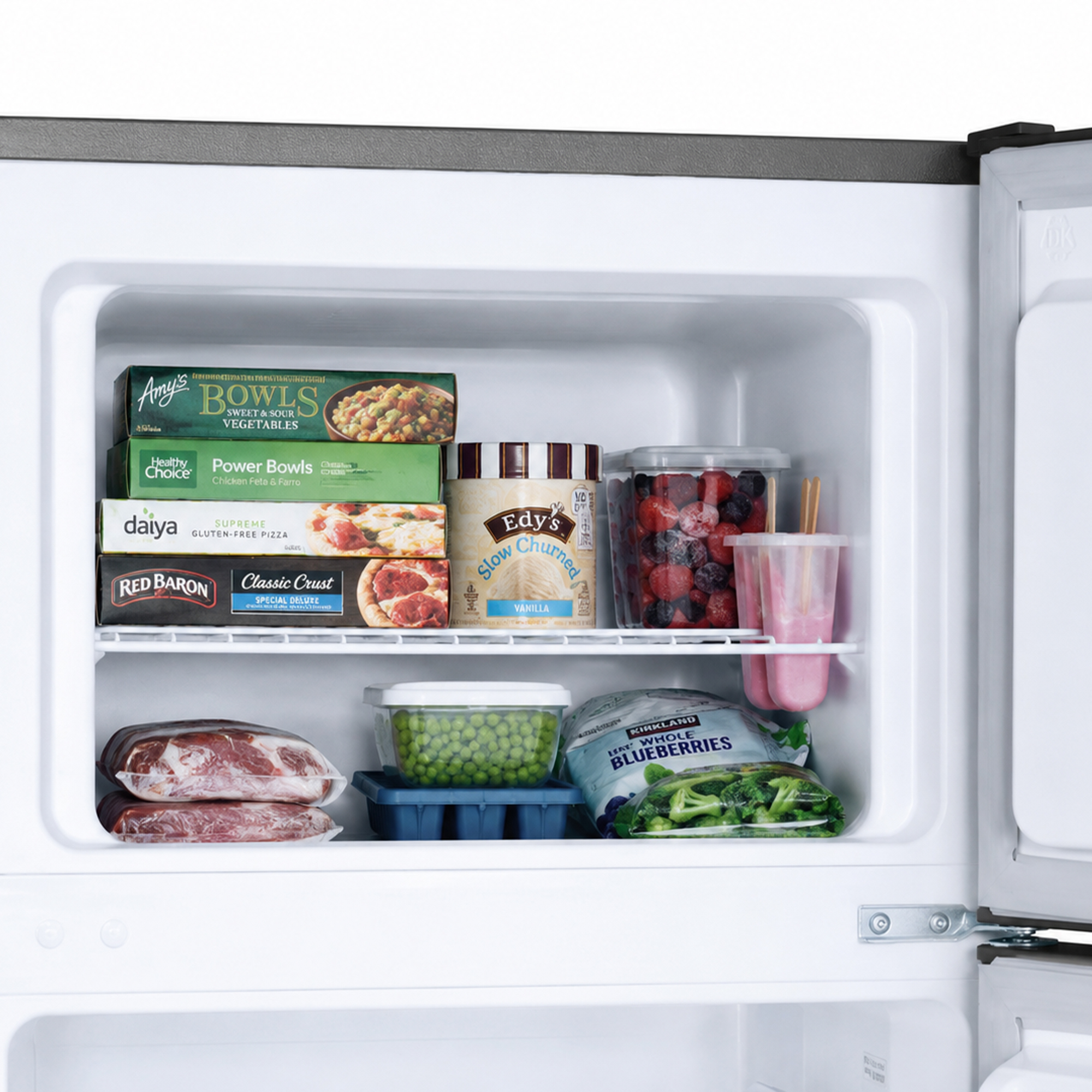 Freezer stocked with frozen foods: vegetables, pizza, ice cream, berries, meat.