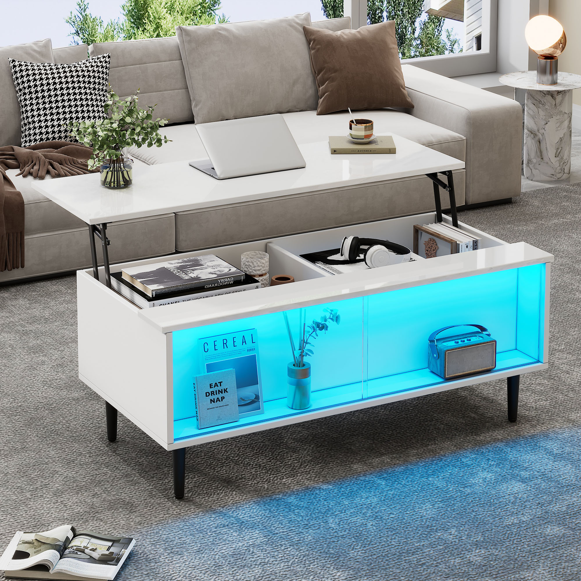Ein weißer Couchtisch mit aufklappbarer Platte, blau beleuchtet, mit Büchern und Kopfhörern.