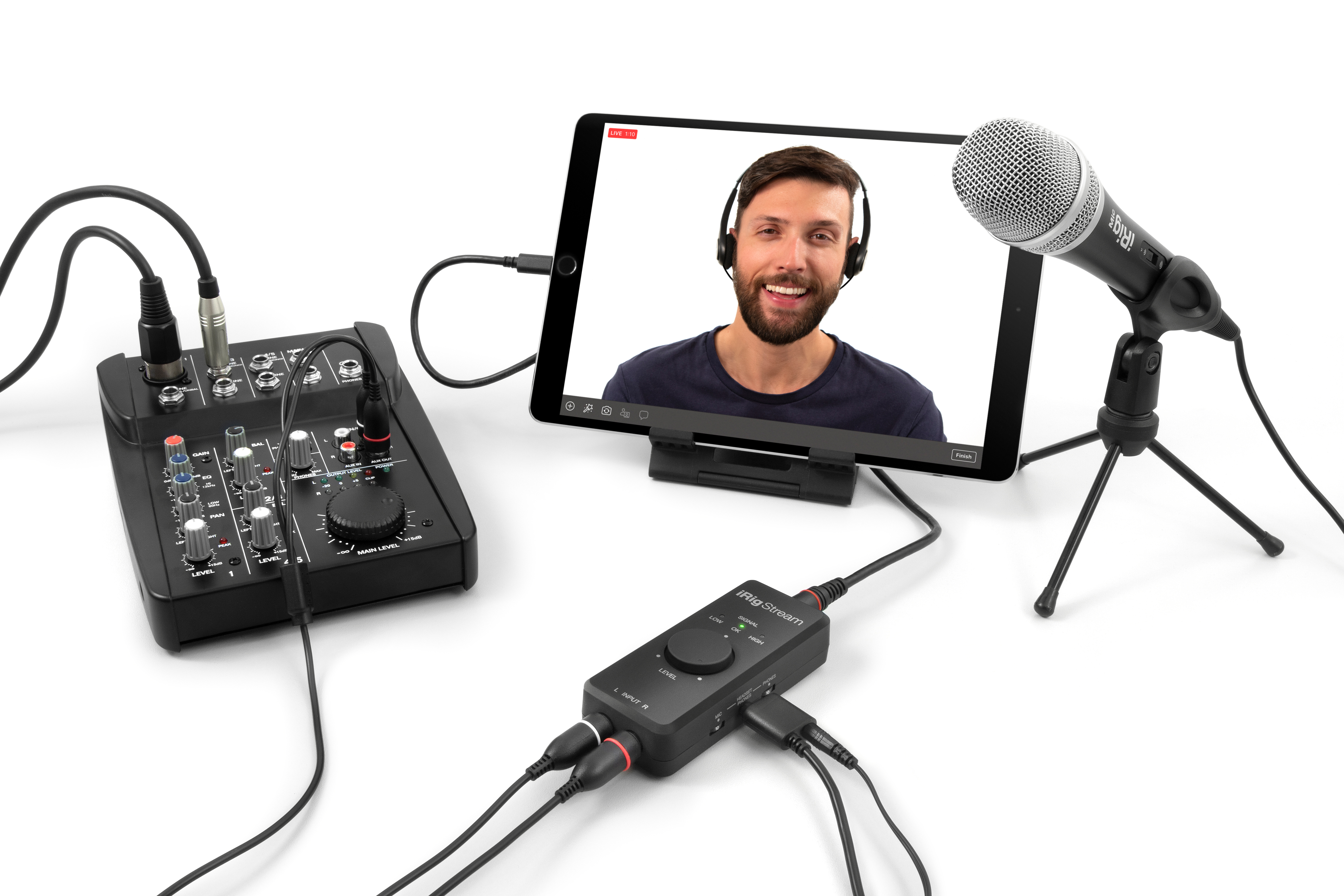 Un uomo con cuffie su un tablet, accanto a un mixer, microfono e interfaccia.