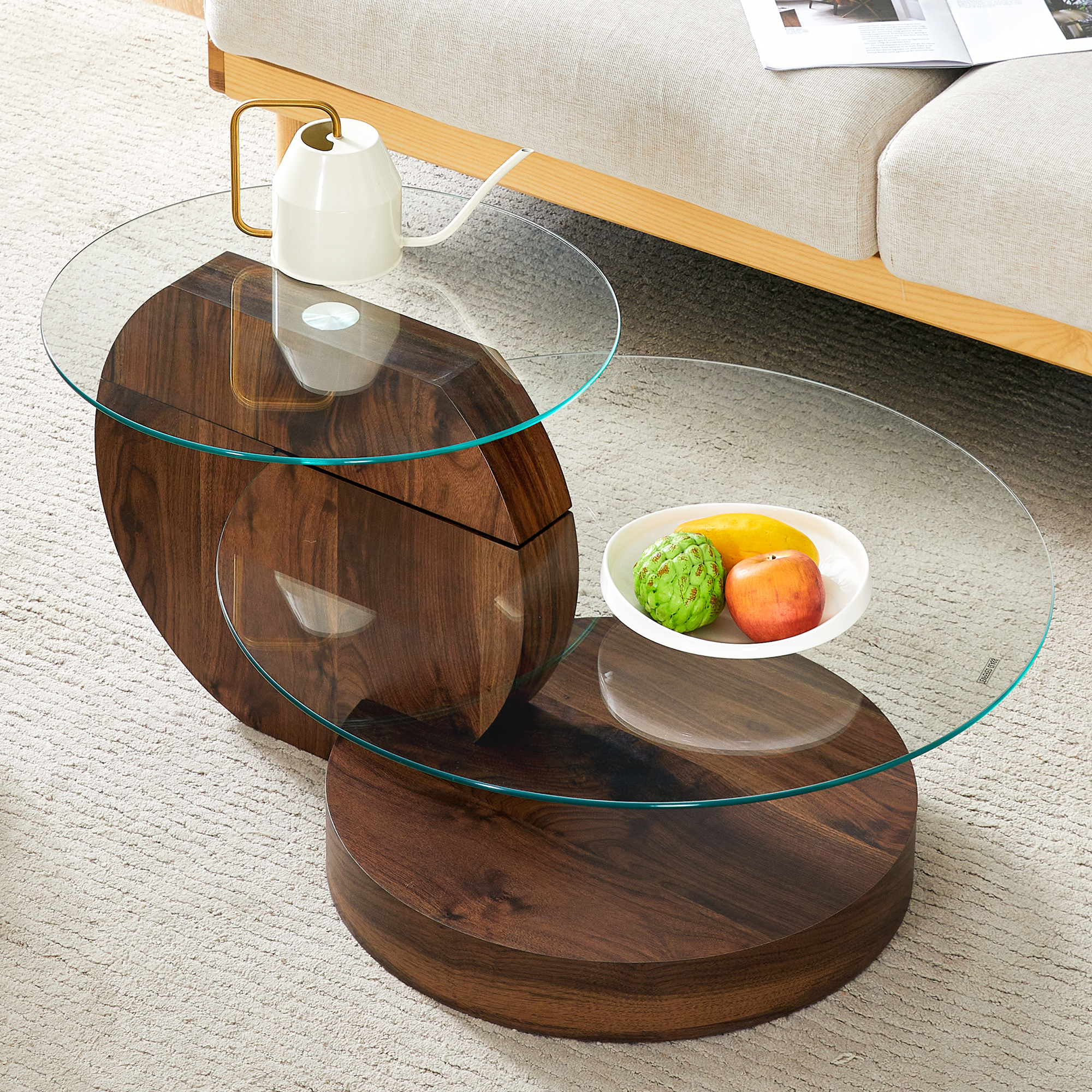 Ein runder Couchtisch aus Glas und dunklem Holz mit Obst und einer Kanne.