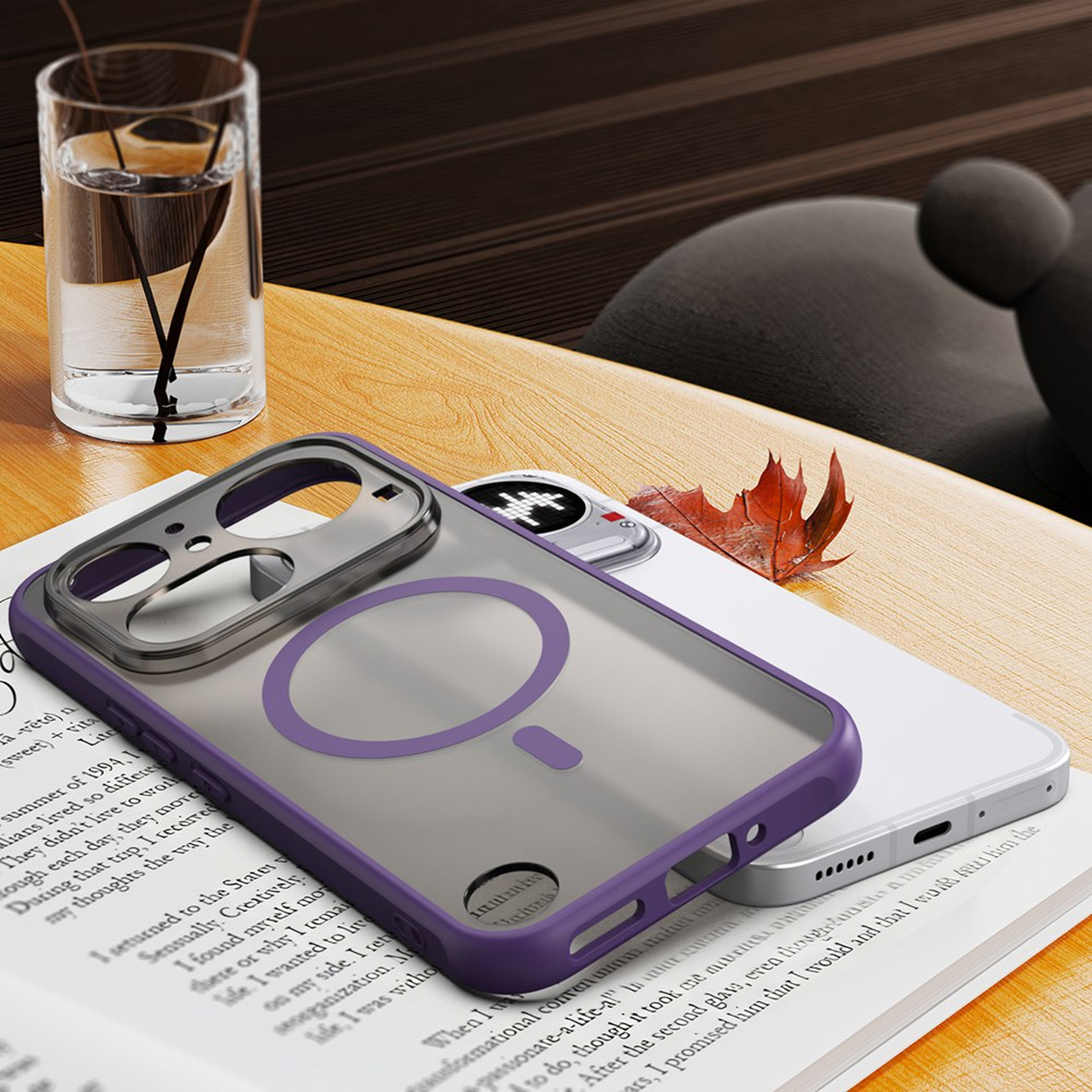 Paarse iPhone hoes met MagSafe op een boek, naast een glas water en een blad.
