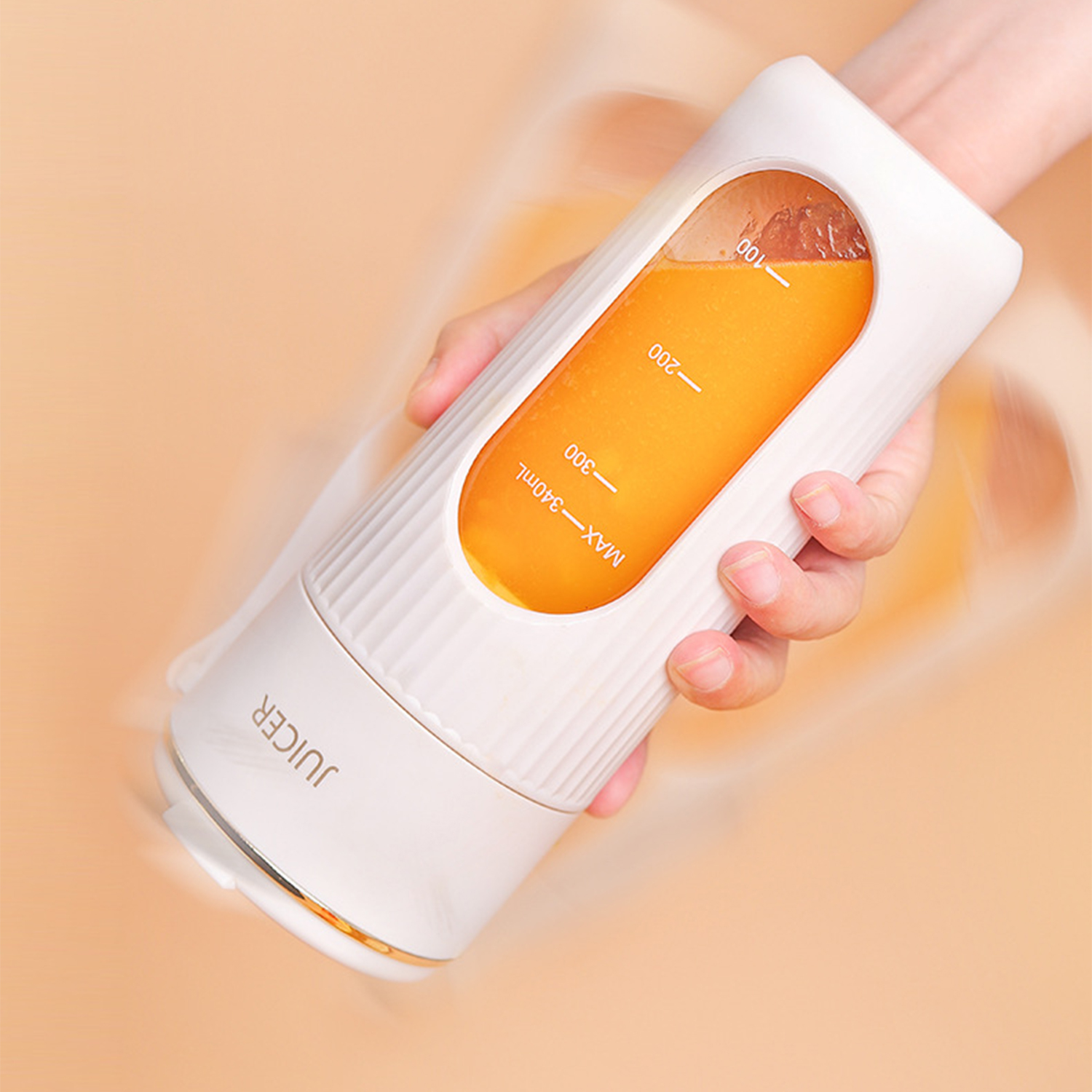 Una mano sostiene una licuadora portátil blanca con jugo amarillo dentro.
